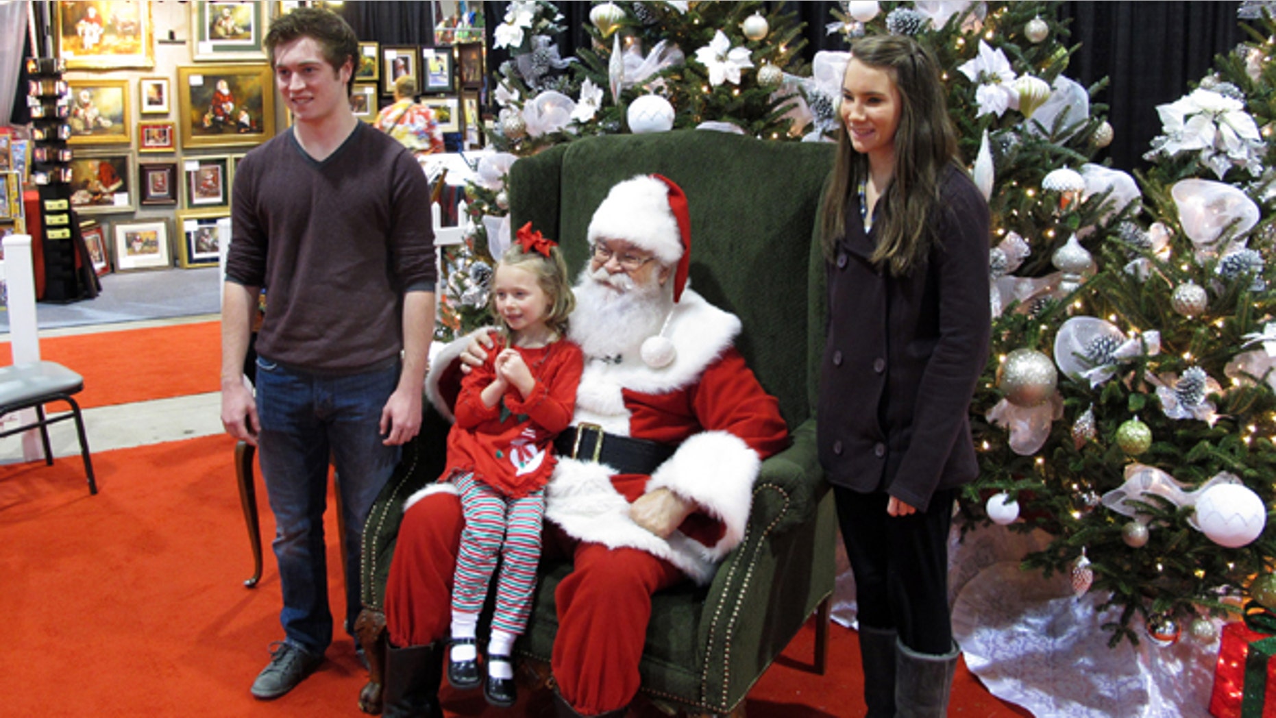 In Nov. 29, 2013 photo taken from video, siblings Maddie, 5, Mackenzie, 15, and Caleb Bunn, 18, from Rocky Mount, N.C., pose for a photo with "Santa" Cliff Snider at the Christmas Carousel show in Raleigh, N.C.