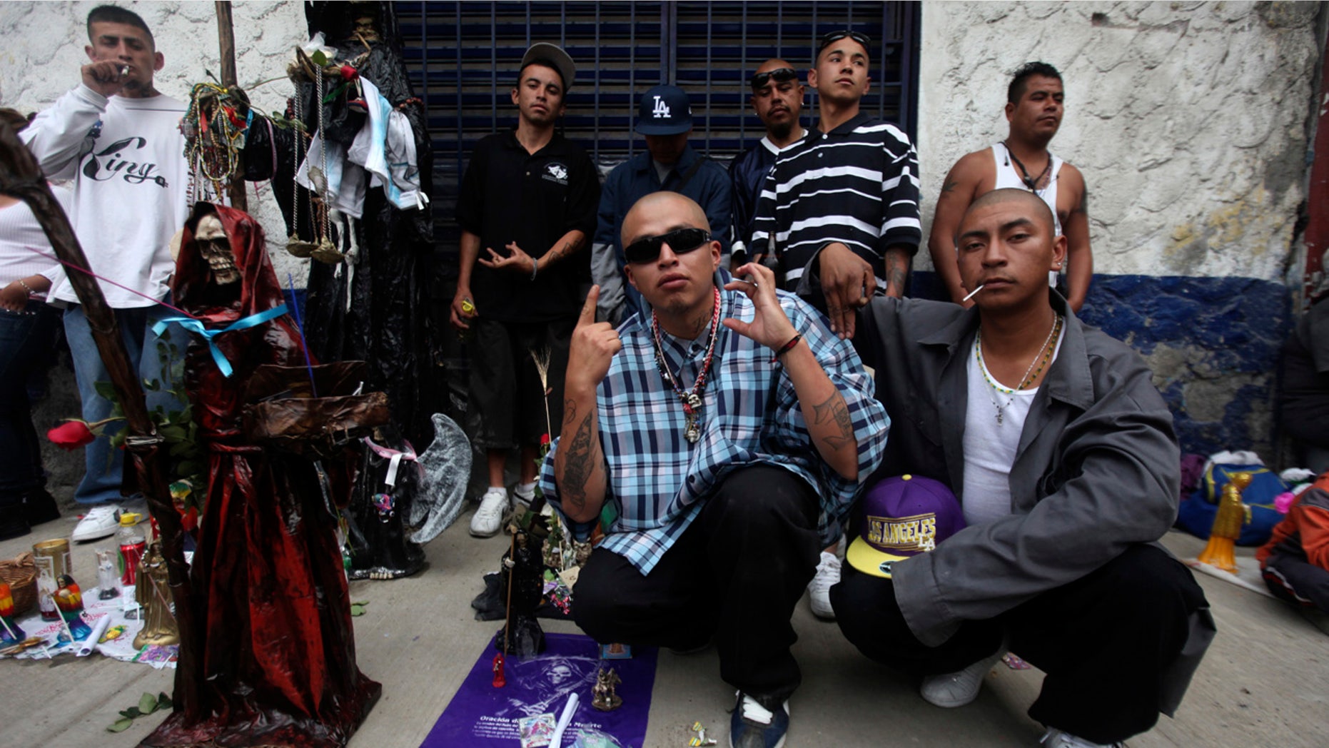 Followers of La Santa Muerte, a cult figure often depicted as a skeletal grim reaper, gesture while posing at the saint's altar in a Mexico City neighborhood.