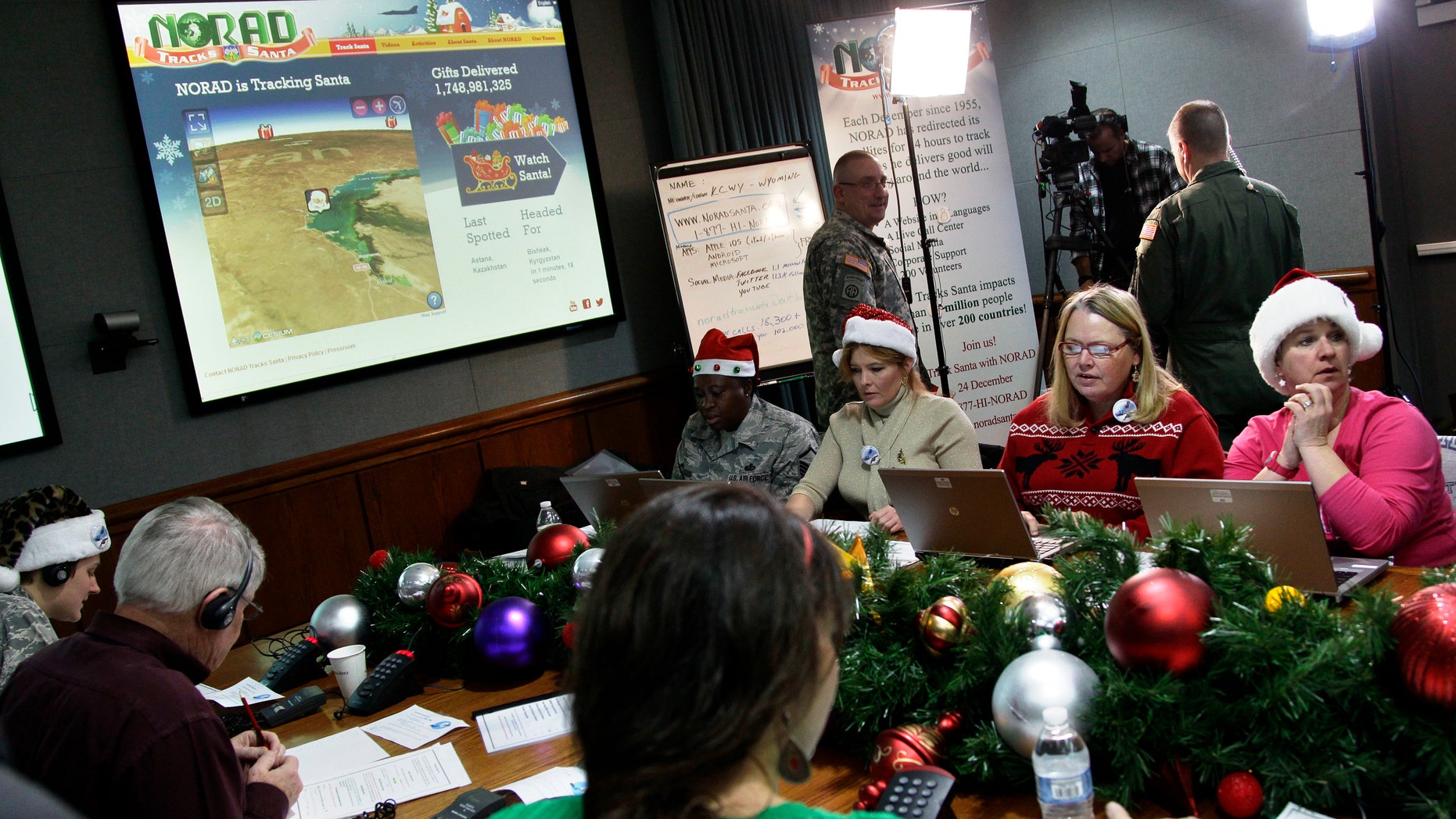 FILE - In this Dec. 24, 2012, file photo, volunteers take phone calls from children asking where Santa is and when he will deliver presents to their house, during the annual NORAD Tracks Santa Operation, at the North American Aerospace Defense Command, or NORAD, at Peterson Air Force Base, in Colorado Springs, Colo.The wildly popular NORAD Tracks Santa operation is launching its 61st run at Peterson Air Force Base, Colorado. Volunteers will answer phone calls and emails and post updates about Santa's storybook world tour on Facebook and Twitter. (AP Photo/Brennan Linsley, File)