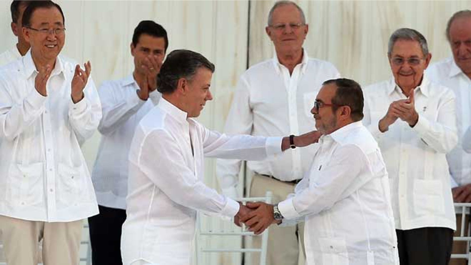 Colombia’s President Juan Manuel Santos, front left, and the top commander of the Revolutionary Armed Forces of Colombia (FARC) Rodrigo Londono, known by the alias Timochenko, shake hands after signing the peace agreement between Colombia’s government and the FARC to end over 50 years of conflict in Cartagena, Colombia, Monday, Sept. 26, 2016. Behind, from left, are U.N. Secretary General Ban Ki Moon, Mexico's President Enrique Pena Nieto, Peru's President Pedro Pablo Kuczynski, Cuba's President Raul Castro, and Spain's former King Juan Carlos. (AP Photo/Fernando Vergara)