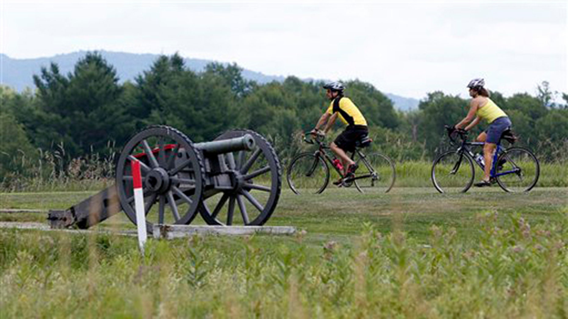 July 2, 2012: Eric Epstien, left, and Isabelle Davidowitz, of Braddock Heights, Md., ride past a cannon on a bike tour of Saratoga National Historical Park in Stillwater, N.Y.