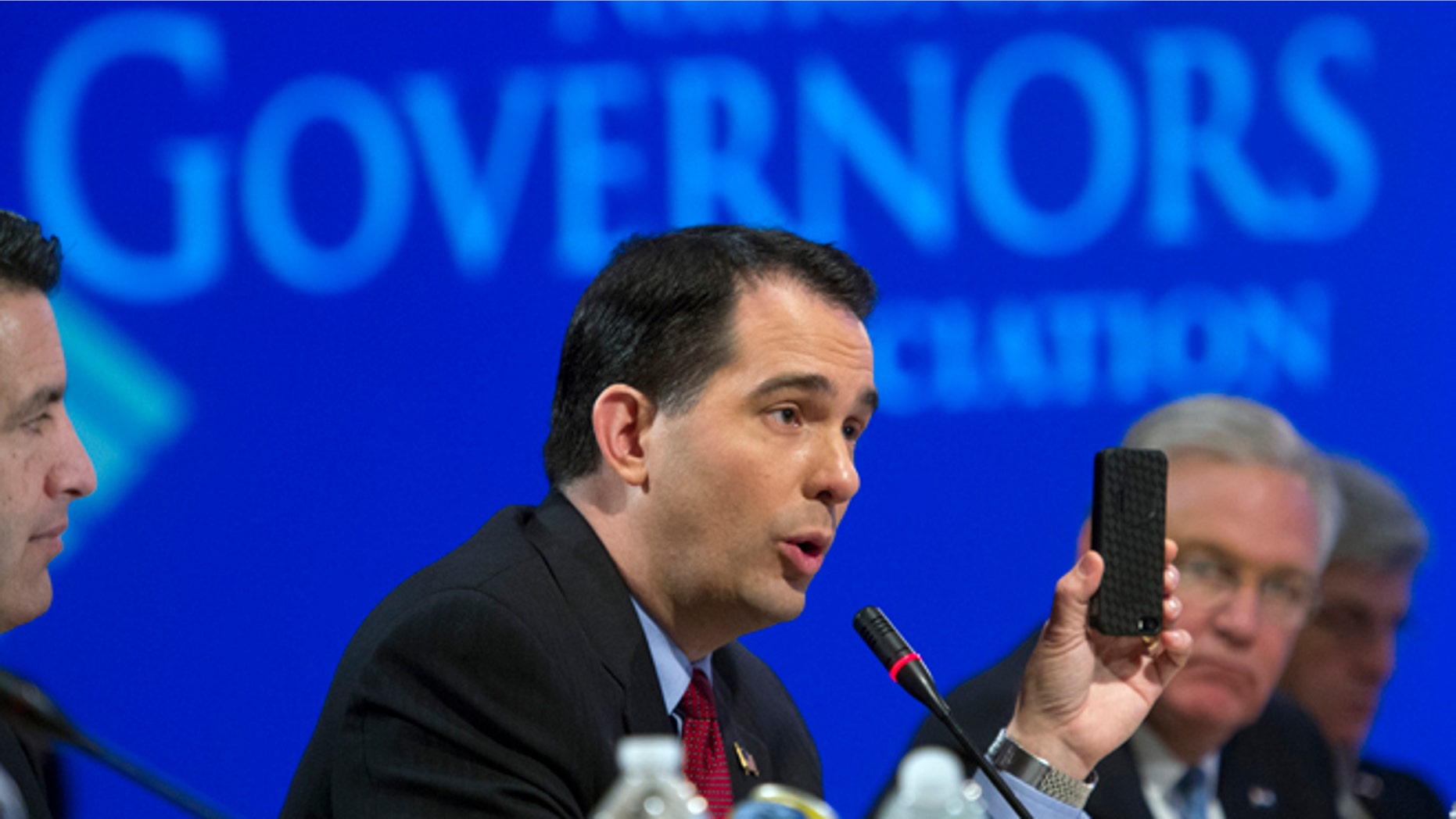 Feb. 23, 2014: Wisconsin Gov. Scott Walker uses a cellphone to illustrate a point about health care plans during a special session on jobs in America during the National Governor's Association Winter Meeting in Washington.