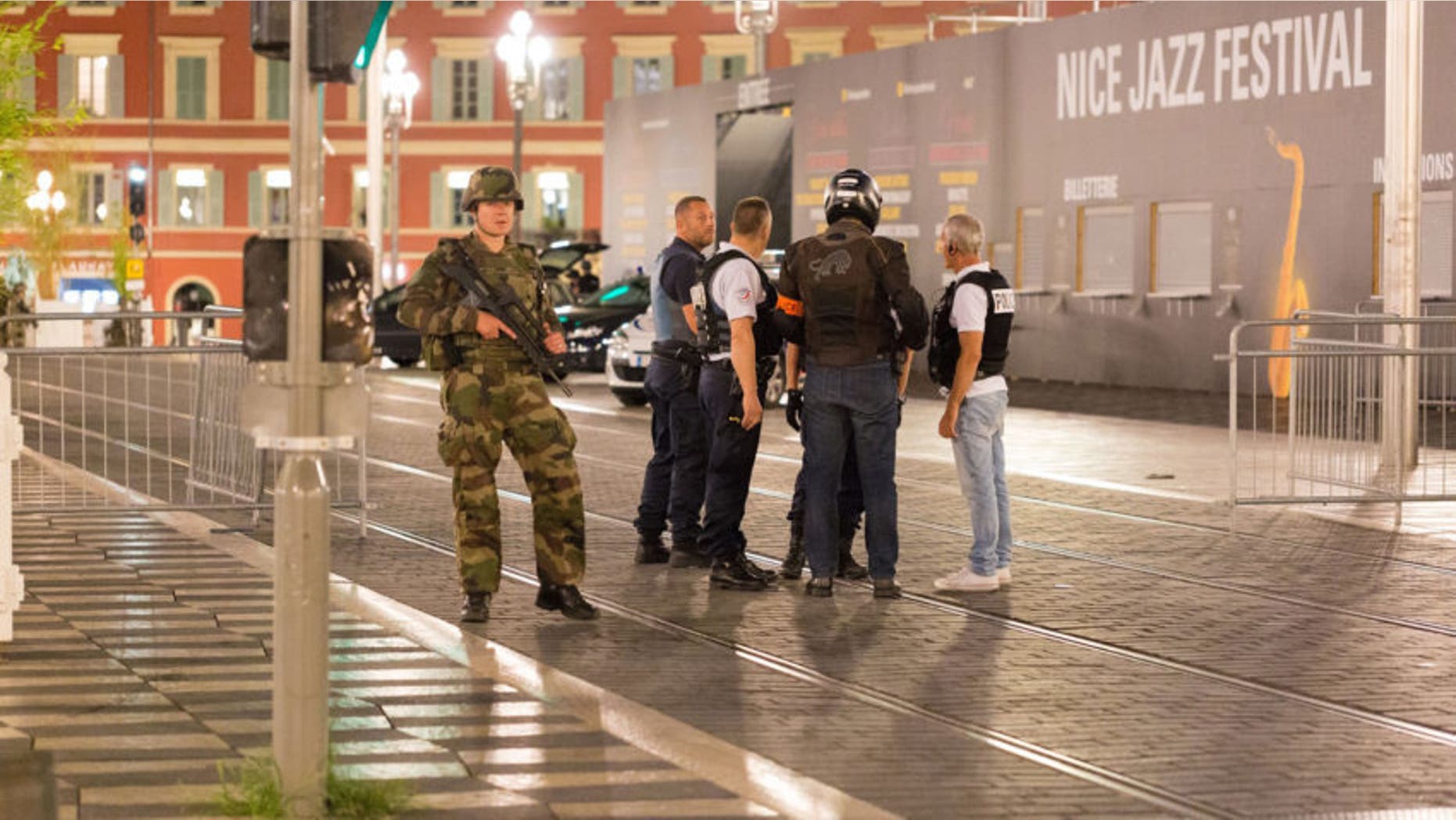 Police officers and a soldier stand by the sealed off area of an attack in Nice, France in wake of a deadly terrorist attack that killed 84 people including 2 American tourists.