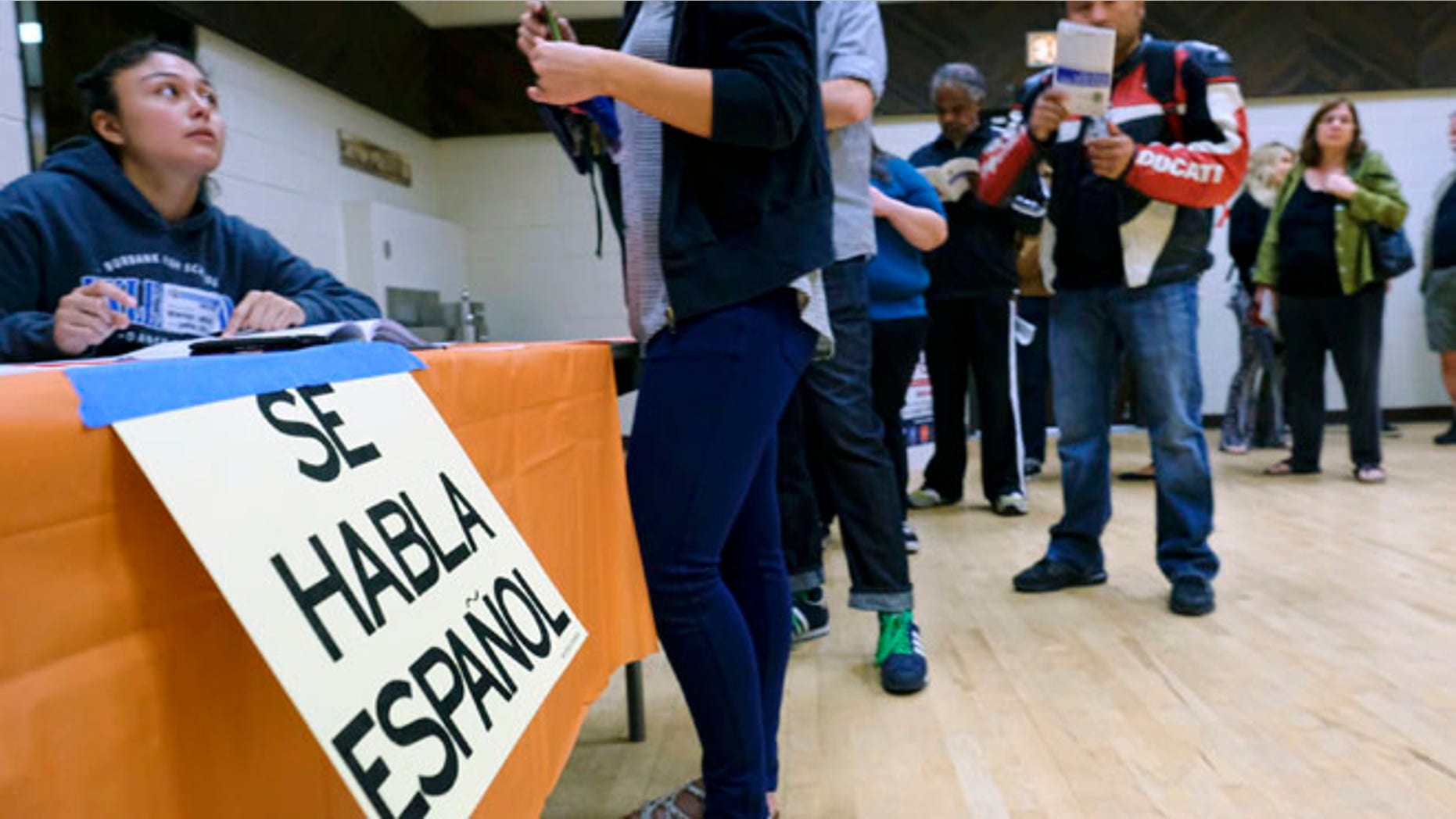 A sign that reads "Spanish is Spoken Here" hangs as voters check in at the North Hollywood Amelia Earhart Regional Library polling station in Los Angeles on Tuesday, Nov. 8, 2016. (AP Photo/Richard Vogel)