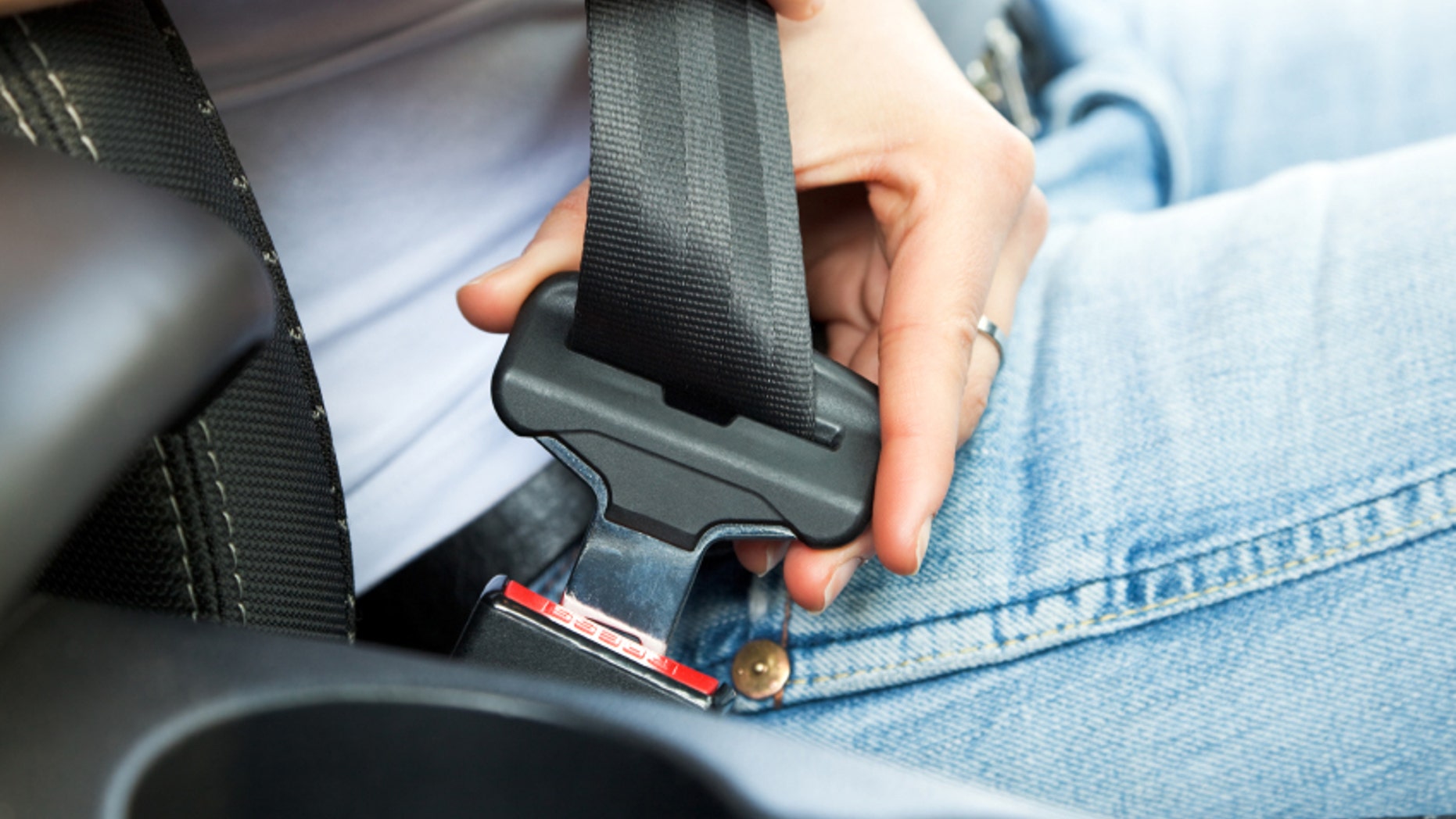 close up of female fastening safety belt in car