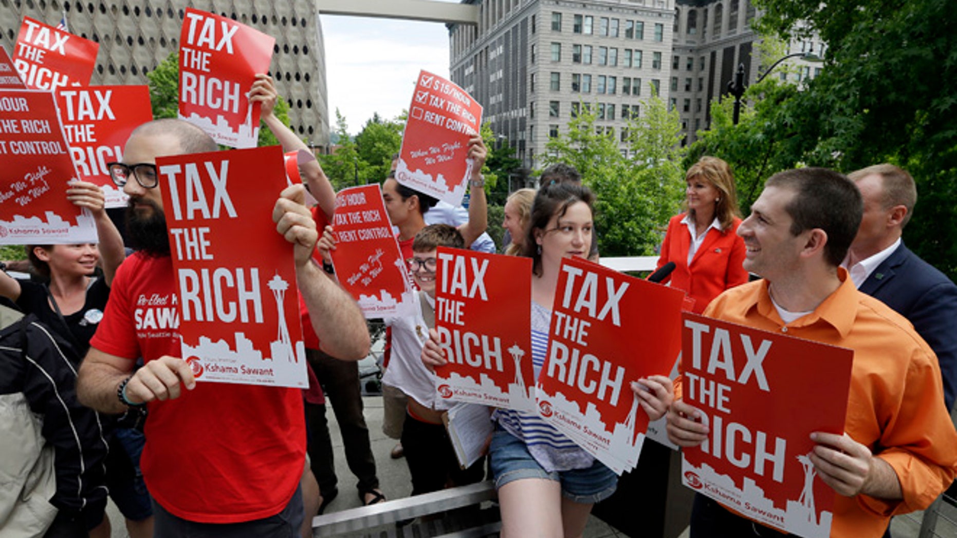 Demonstrators holding signs in favor of a new city income tax on the at a Seattle City Council Monday, July 10.