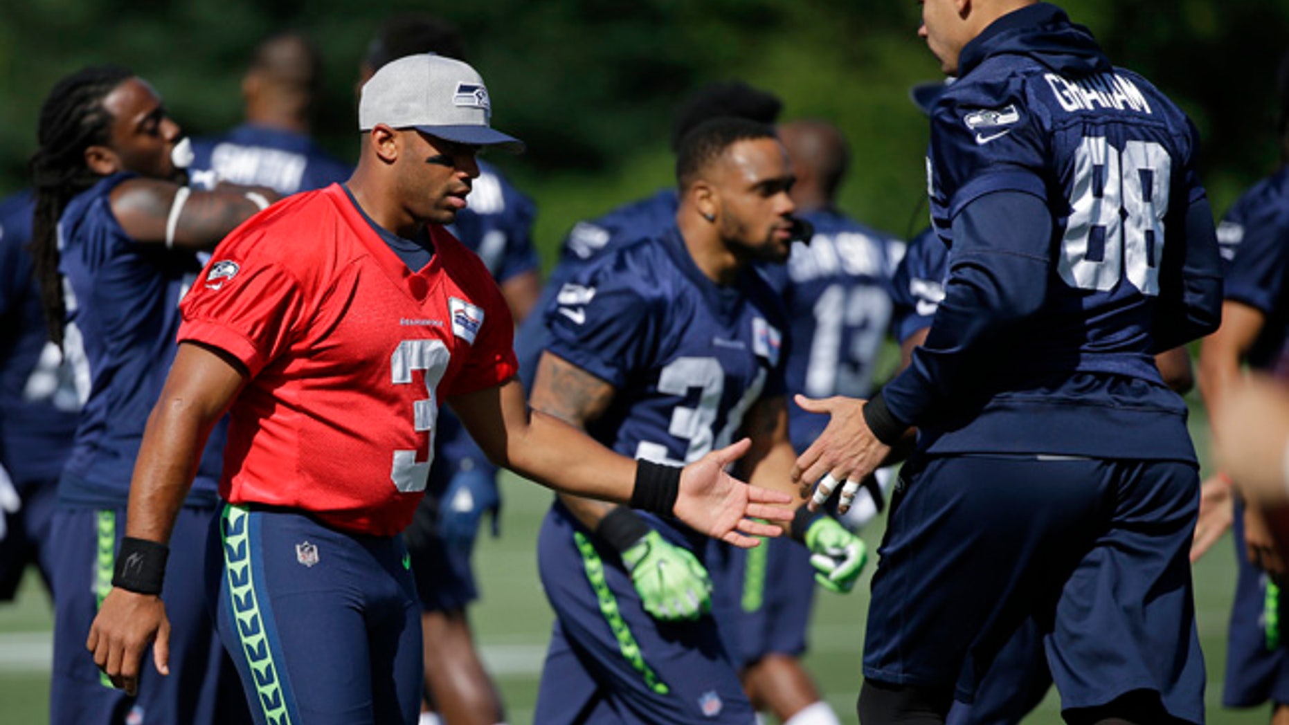 Seattle Seahawks quarterback Russell Wilson, left, greets tight end Jimmy Graham (88) at NFL football training camp, Sunday, July 30, 2017, in Renton, Wash. (AP Photo/Ted S. Warren)