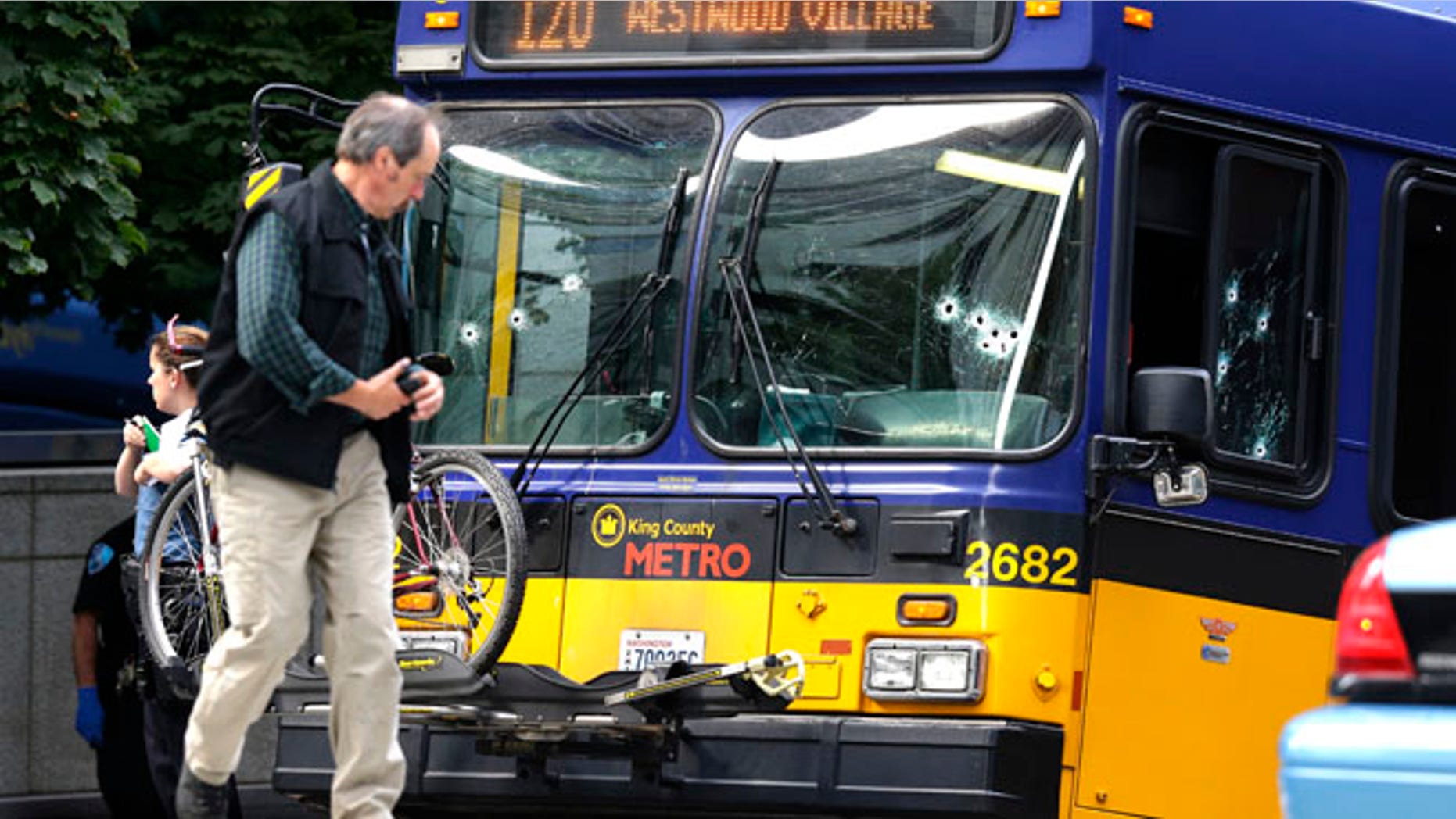 Aug. 12, 2013: An official walks next to a King Co. Metro bus with multiple bullet holes in its windshield and side window, after a bus driver was shot Monday in downtown Seattle. A man who had shot the driver of another bus was shot by officers after he boarded the bus shown here.