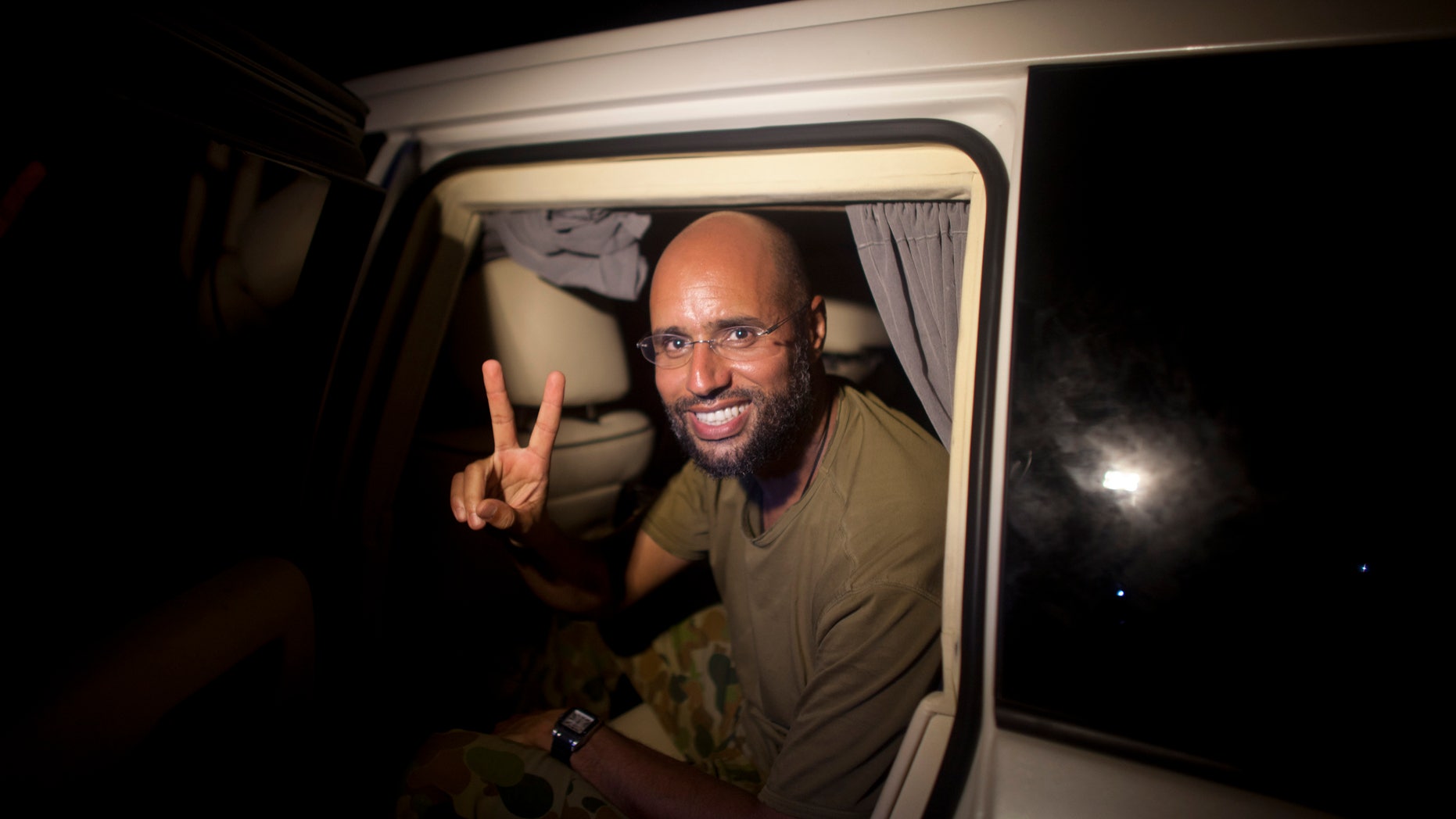 In this Tuesday, Aug. 23, 2011 file photo, Muammar Qaddafi's son Seif al-Islam makes a victory sign as he appears at the Rixos hotel in Tripoli, Libya. A Libyan commander told reporters Saturday, Nov. 19, 2011 that Seif al-Islam Gadhafi has been arrested in south Libya.