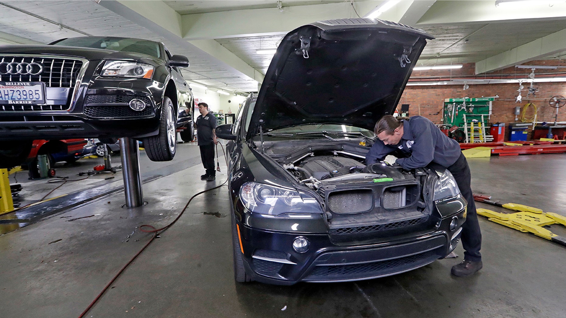 In this Wednesday, April 25, 2018, photo, auto technician Anthony Sterns, right, works to replace the coolant expansion tank on a 2011 BMW at the Fat City German Car service shop in Seattle. At first, dumping your old car might seem like a no-brainer, and you can't help picturing how good you would look in that new car. But automotive experts say you'll almost always come out ahead, at least financially, by fixing old faithful. (AP Photo/Elaine Thompson)