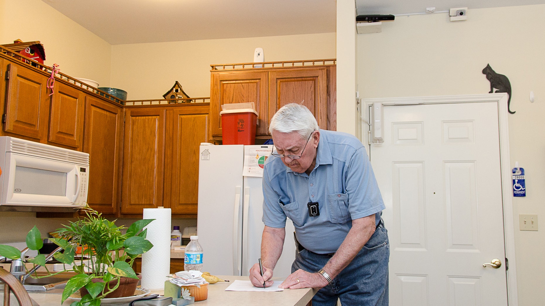 Bob Harrison writes in his TigerPlace apartment in Columbia, Mo., as different sensors mounted near the ceiling record activity patterns. The sensor technology is unobtrusive and does not interfere with his everyday tasks.