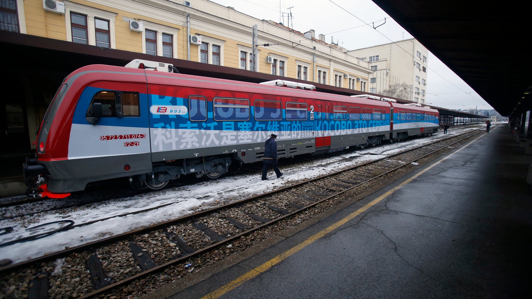 A railroad worker walks by a train decorated with letters that read "Kosovo is Serbian."