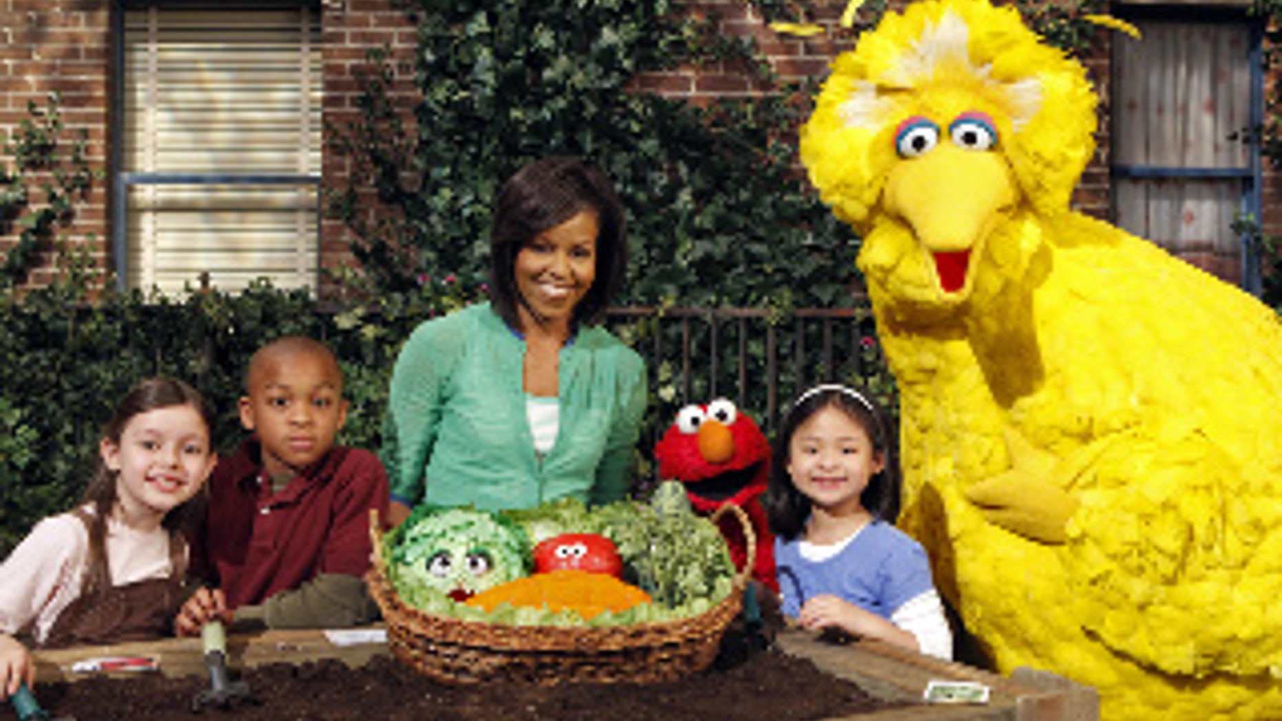 This May 5, 2009 photo released by Sesame Workshop shows first lady Michelle Obama, third from left, with Big Bird, Elmo, Muppets & cast in "Michelle Obama Plants A Garden" in Astoria, N.Y. Mrs. Obama appears on "Sesame Street" Tuesday, Nov. 10, 2009, and recently taped an episode of "Iron Chef America," just two of the varied platforms she's been using lately to get her healthy-eating message out to the masses. (AP Photo/Sesame Workshop, Richard Termine)