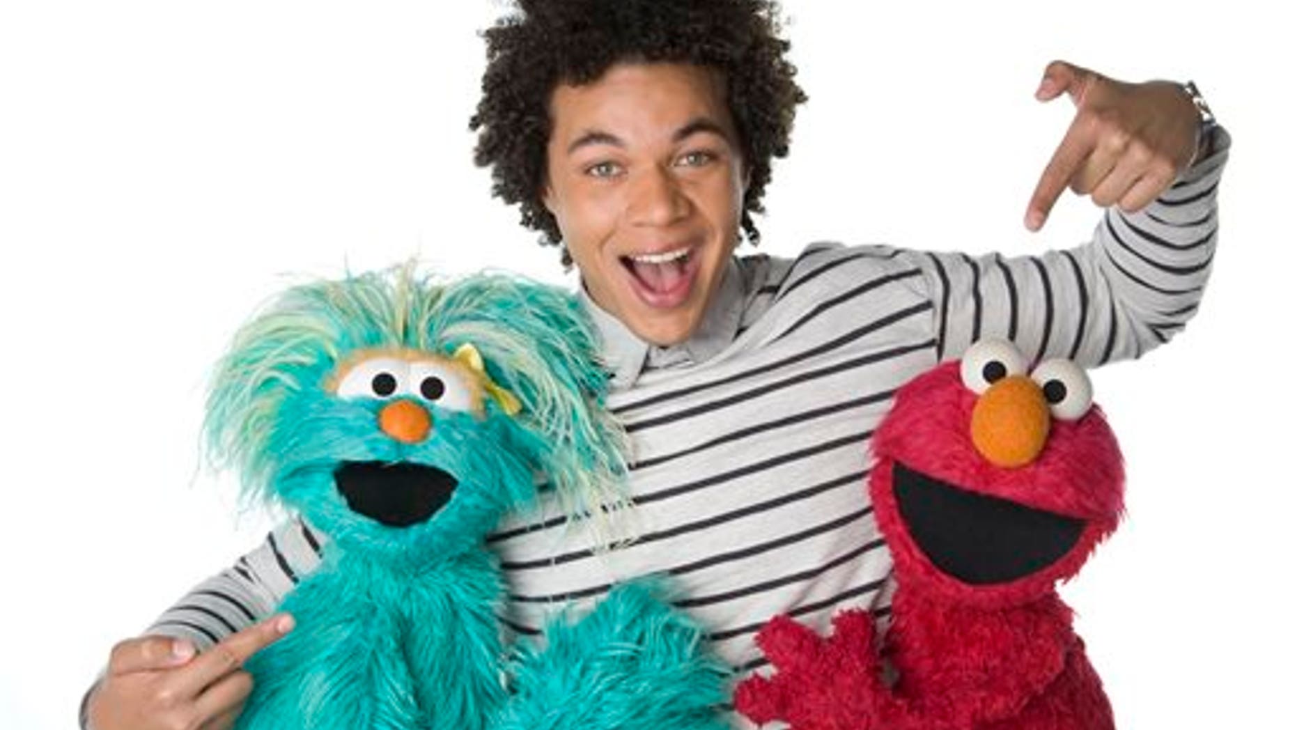 This April 2013 photo released by Sesame Workshop shows Puerto Rican actor Ismael Cruz Cordova, 26, of "Sesame Street," posing with muppets Rosita, left, and Elmo in New York. Cruz plays Mando, a young Latino writer who interacts with the puppets and also loves technology. (AP Photo/Sesame Workshop, Gil Vaknin)