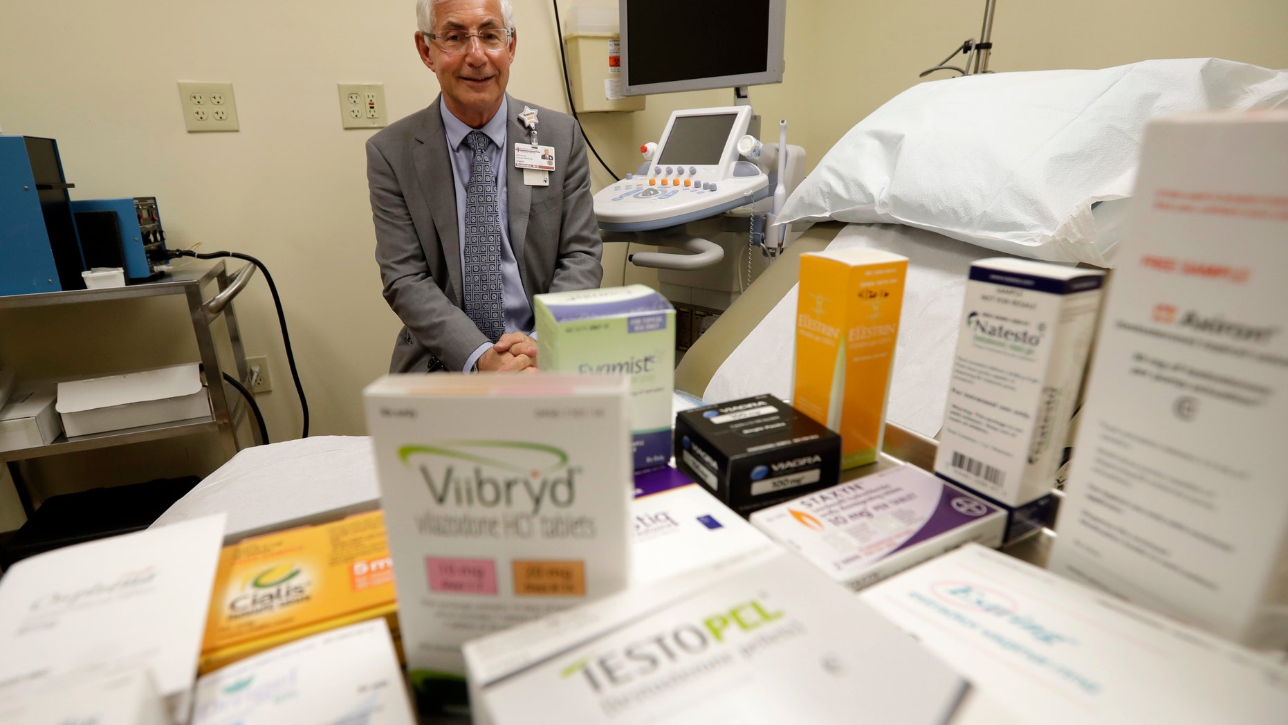 In this Tuesday, Nov. 29, 2016 photo, Dr. Irwin Goldstein poses in his office in San Diego behind a display of medicine for impotence and for sexual problems. For couples who can't afford the soaring prices for the prescriptions, some take a big risk, buying "herbal Viagra" at gas stations or ordering Viagra online from "Canadian pharmacies" that likely sell counterfeit drugs made in poor countries, says Goldstein, director of San Diego Sexual Medicine. (AP Photo/Gregory Bull)