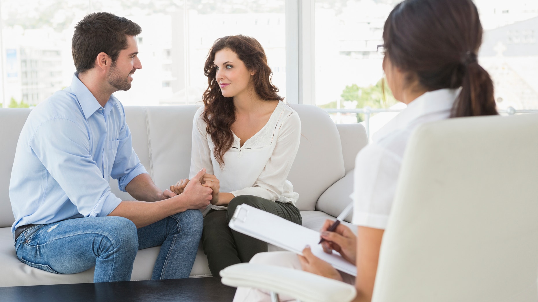 Reconciled couple smiling at each other in the therapist office