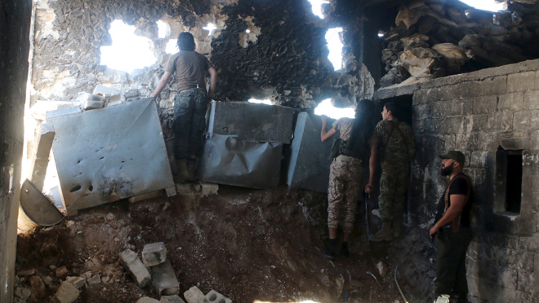 APRIL 19: Harakat Nour al-Din al-Zenki fighters look out inside a damaged building in Handarat area, north of Aleppo Syria April 19, 2016.