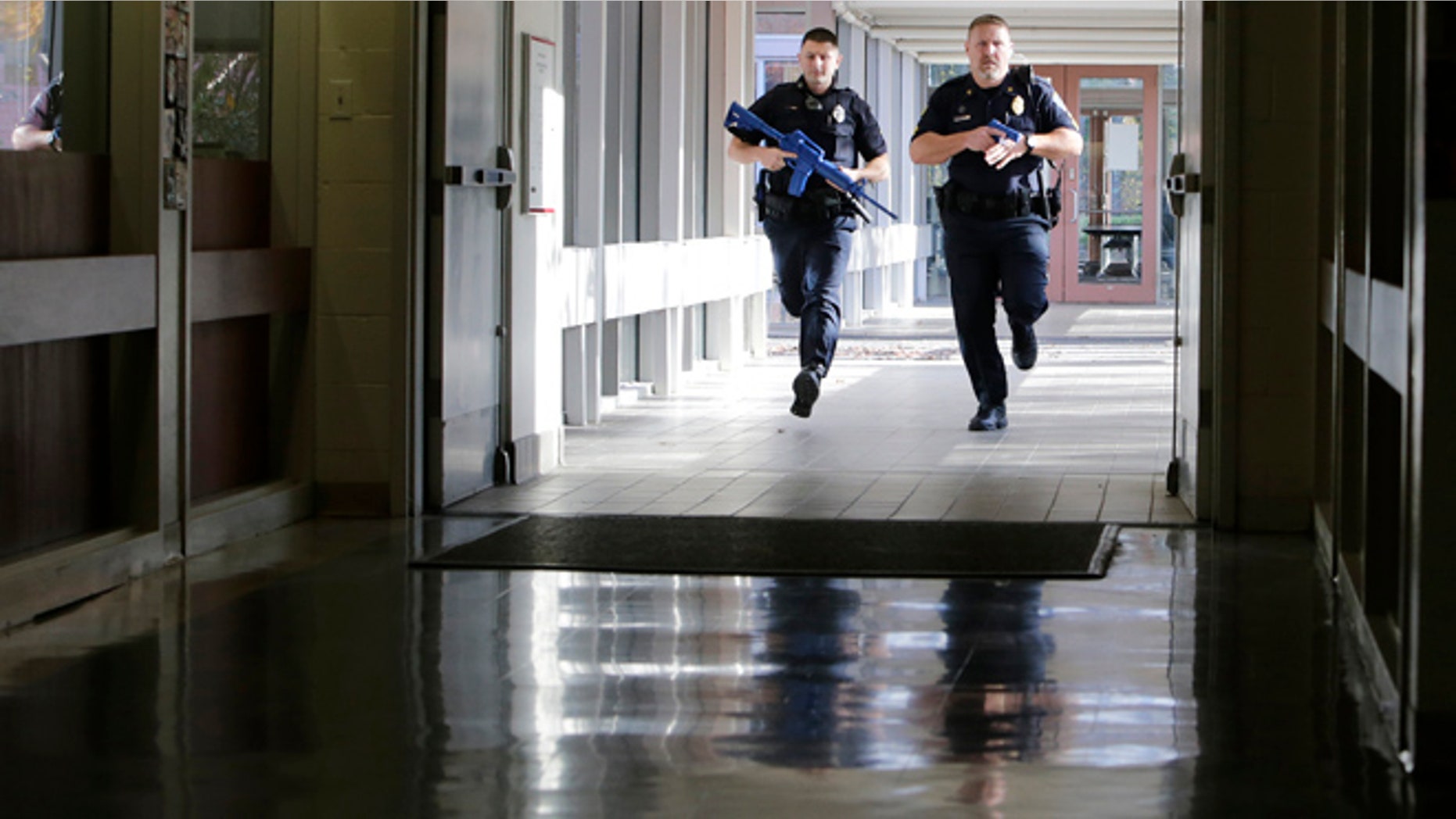 Officers from the Methuen, Mass., police department carry training weapons as they search the halls of a school during a demonstration in Methuen, Tuesday, Nov. 11, 2014. School and police officials have unveiled a new system to detect and track a gunman that they say is the first in operation in a public school. (AP Photo/Charles Krupa)