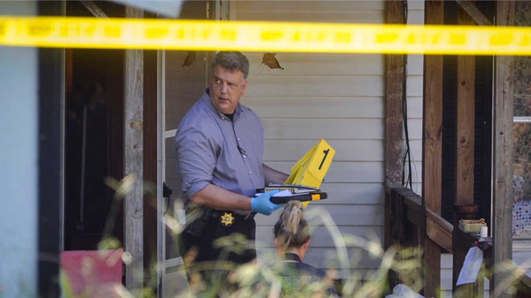Law enforcement officials investigate the scene of a shooting at a home in Suwanee, Ga.
