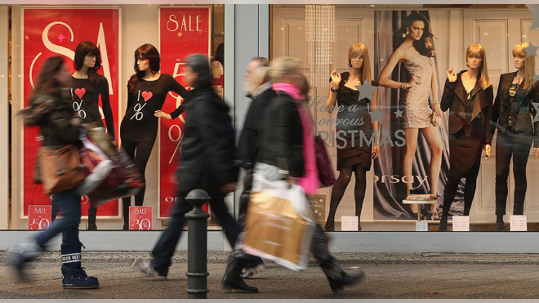 BERLIN, GERMANY - DECEMBER 17: People walk by a clothing store adevertising sales on a shopping street in Steglitz district on December 17, 2012 in Berlin, Germany. Retailers are hoping for a strong Christmas season in Germany, one of the few countries whose economy has so far weathered the current Eurozone debt crisis relatively well. (Photo by Sean Gallup/Getty Images)