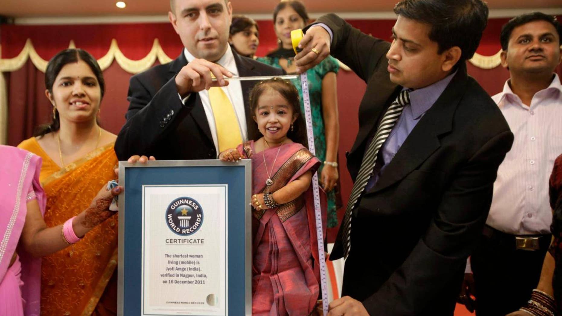 Guinness World Records adjudicator Rob Molloy, center, and Dr. Manoj Pahukar of Wockhardt hospital, right, measures Jyoti Amge in Nagpur, India, Friday, Dec. 16, 2011. Amge, 18, is now eligible under the Guinness World Record guidelines for the "Shortest Woman in the world" title measuring 2 feet. (AP Photo/Manish Swarup)