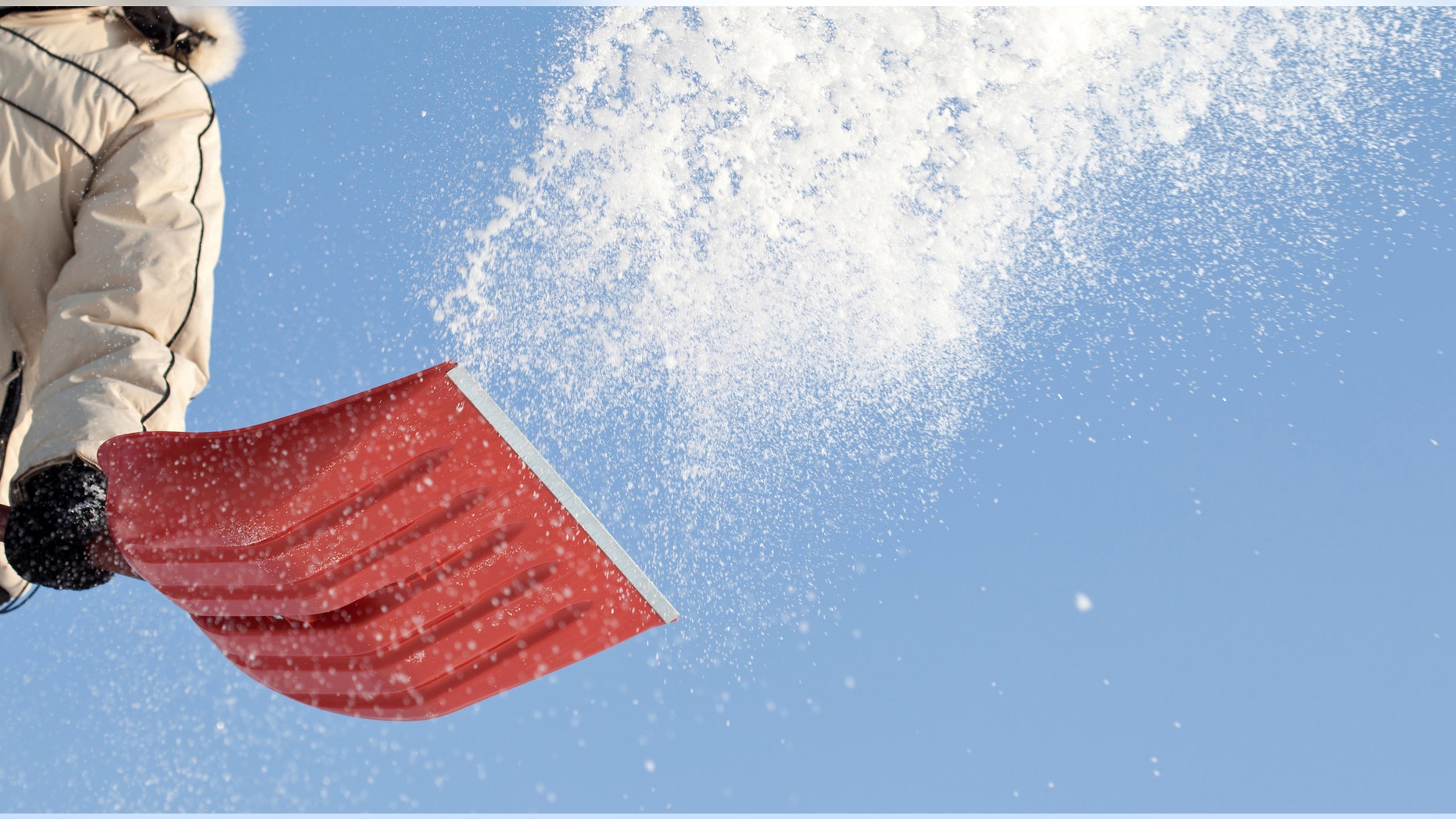 Throwing snow with a snowshovel against blue sky
