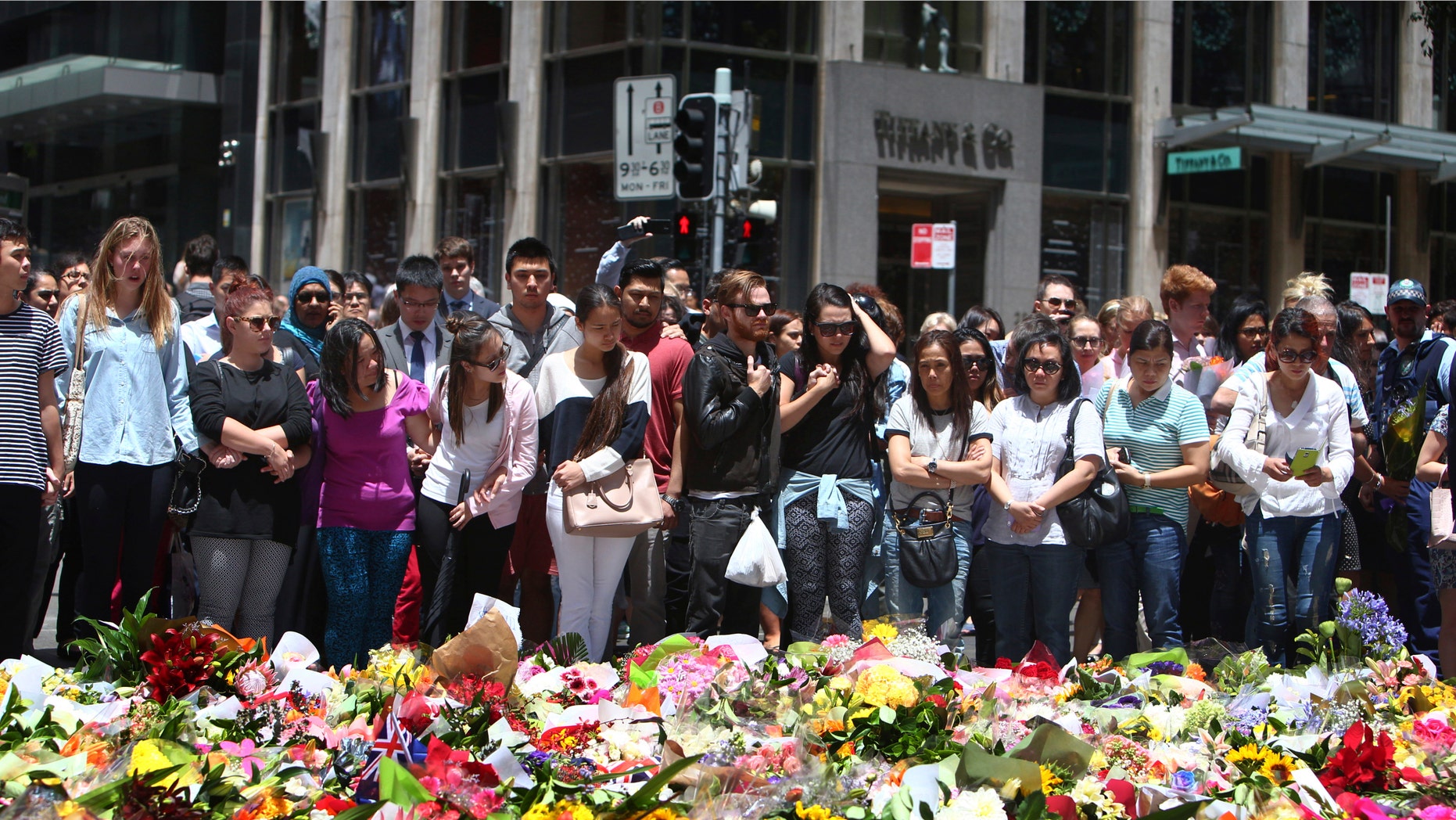 Dec. 16, 2014: Staff members from the Lindt Chocolat Cafe with their arms linked pay tribute to their colleague who lost his live during a siege at the popular coffee shop at Martin Place in the central business district of Sydney, Australia.
