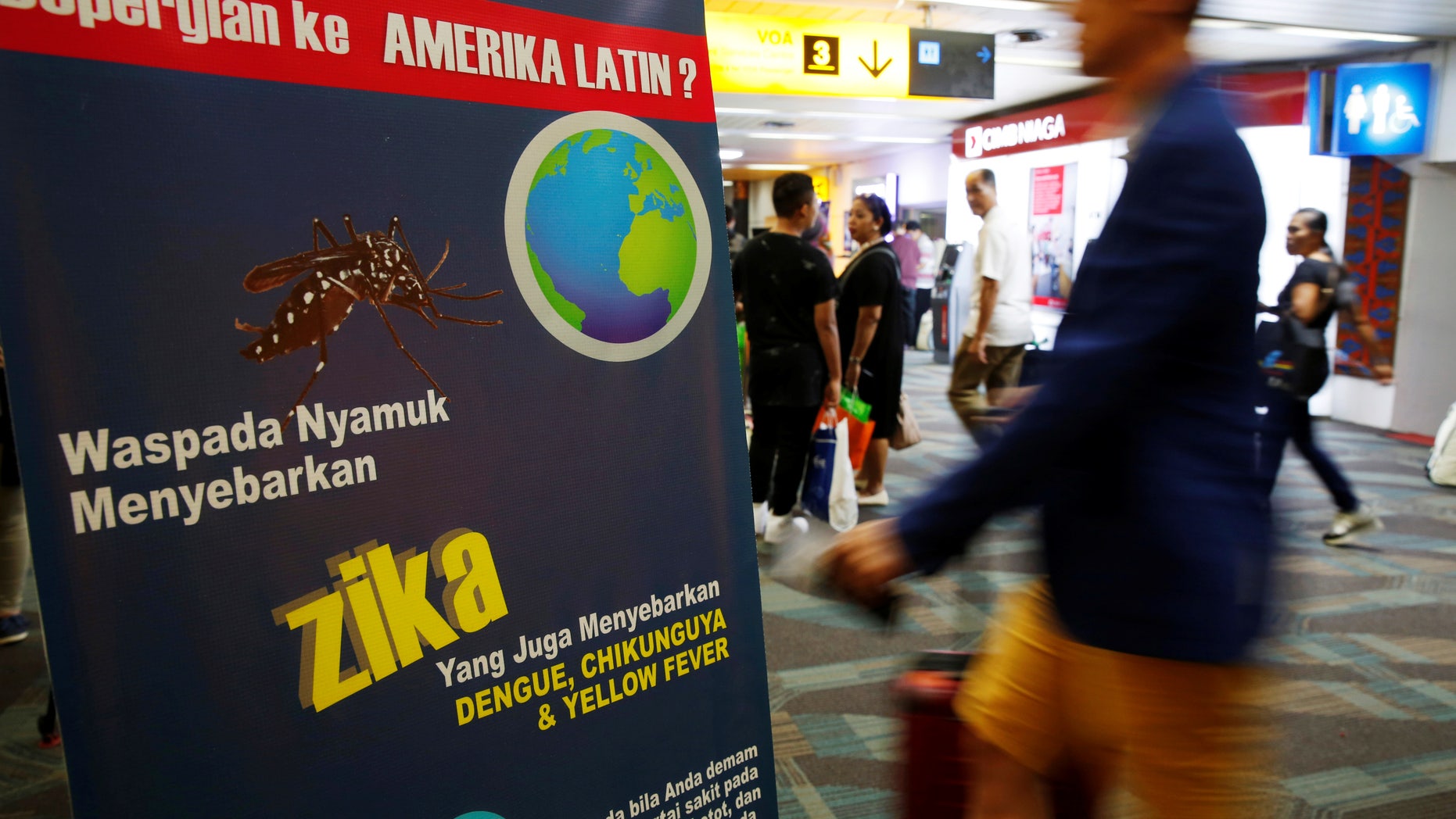 Passengers arriving from Singapore walk near a banner about Zika virus at the Soekarno-Hatta airport in Jakarta, Indonesia, August 30, 2016. The banner reads, "Beware of mosquitoes that spread Zika virus."