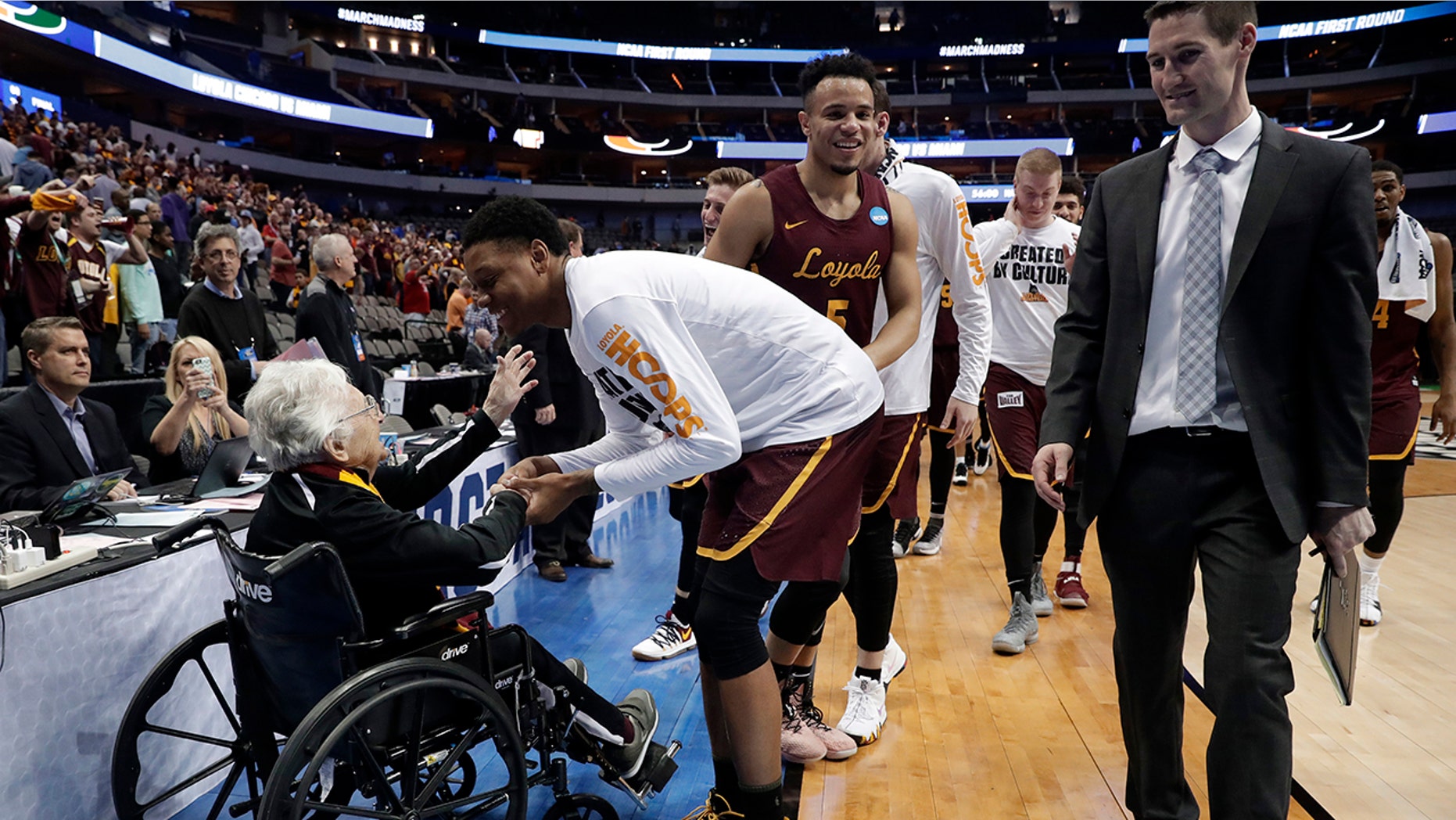 Sister Jean Dolores Schmidt, left, greets the Loyola-Chicago basketball team as they walk off the court after their win over Miami in a first-round game at the NCAA college basketball tournament in Dallas, March 15, 2018.
