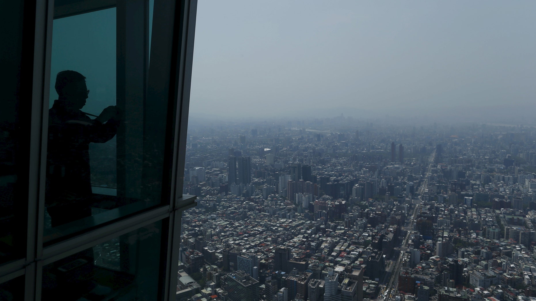 File photo - A tourist takes a photo of the city skyline from the Taipei 101 skyscraper building in Taipei, Taiwan March 29, 2016. (REUTERS/Tyrone Siu)