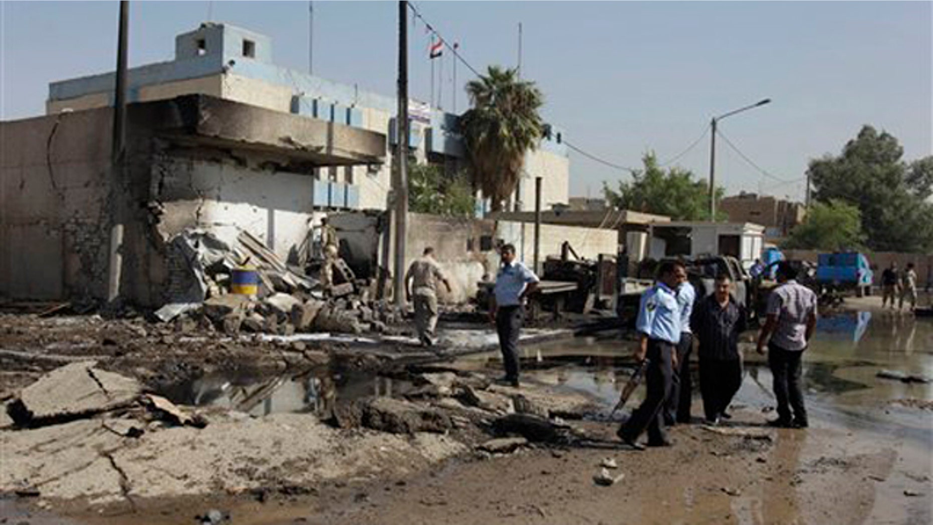 Iraqi security forces inspect a crater caused by a car bomb attack in front of a police station in Baghdad, Iraq, Wednesday, Oct. 12, 2011. A slew of bombings targeting Iraqi police in Baghdad on Wednesday morning killed 12 people and wounded more than 20, Iraqi officials said.