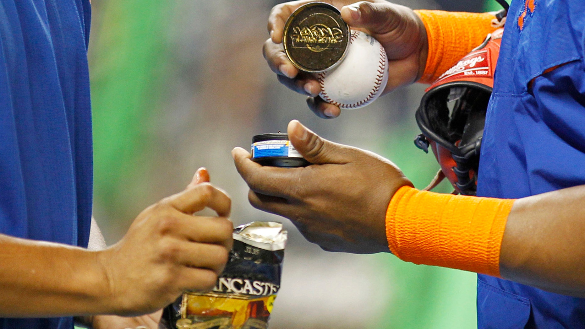 FILE - In this Sept. 5, 2015, file photo, New York Mets players hold tobacco products during batting practice before the team's baseball game against the Miami Marlins in Miami.