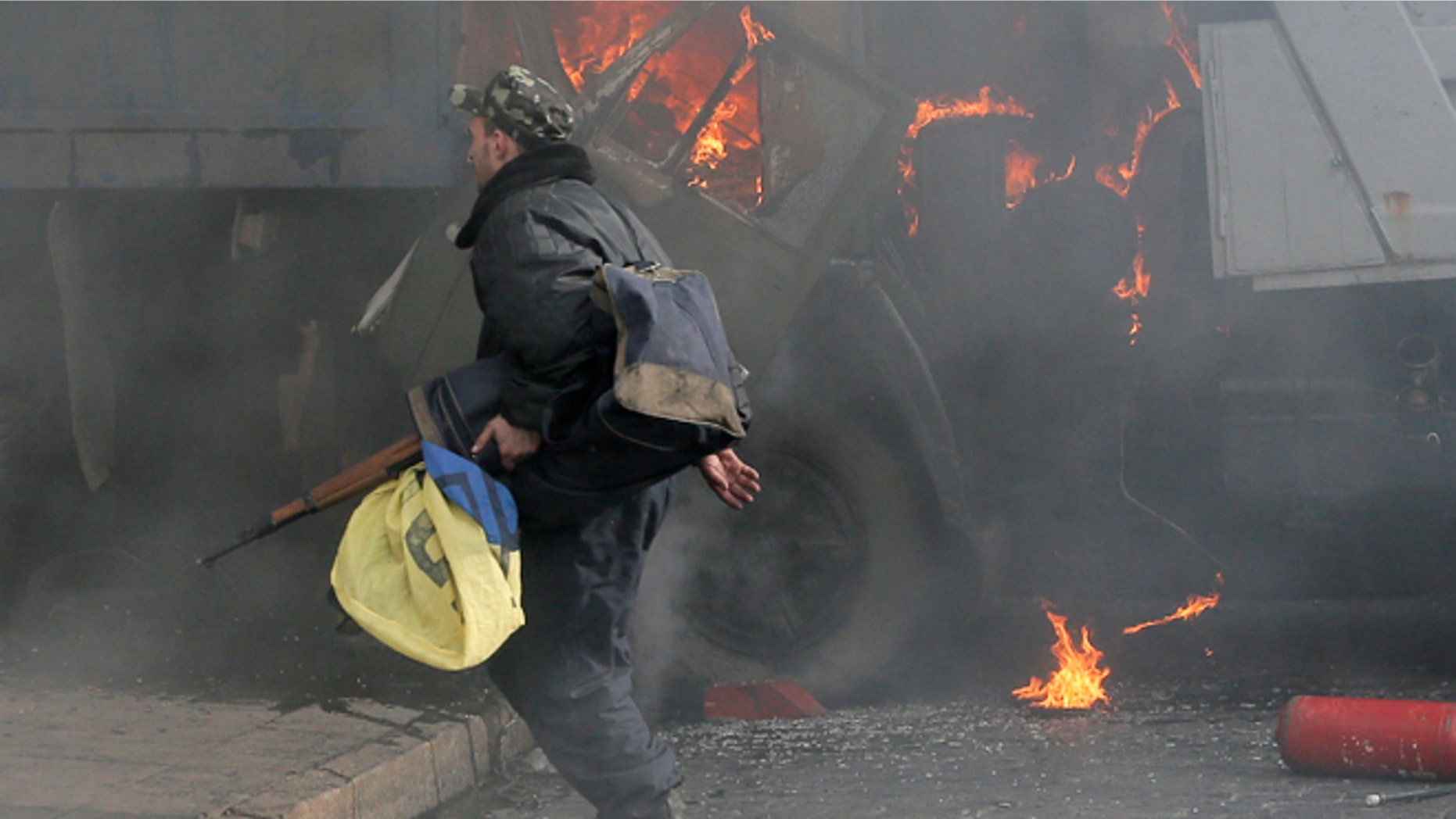 Feb. 21, 2014 In this file photo, a man with a gun runs along a street during a clash between opposition protesters and riot police at a burning barricades near the Presidential office in Kiev, Ukraine.