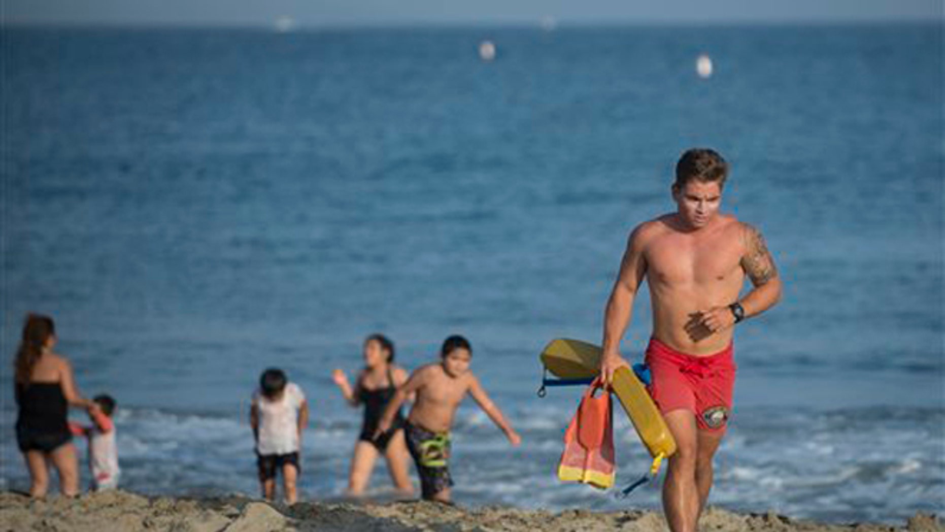 In this Sunday, May 29, 2016, photo, a lifeguard warns beach goers to stay out of the water at Corona del Mar beach in Newport Beach, Calif.