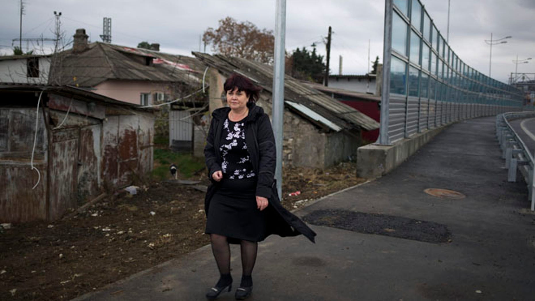 Nov. 27, 2013: Irina Kharchenko walks away from her house beside the screen separating the yard of her house and a federal highway in the village Vesyoloye outside Sochi, Russia. As the Winter Games are getting closer, many Sochi residents are complaining that their living conditions only got worse and that authorities are deaf to their grievances.
