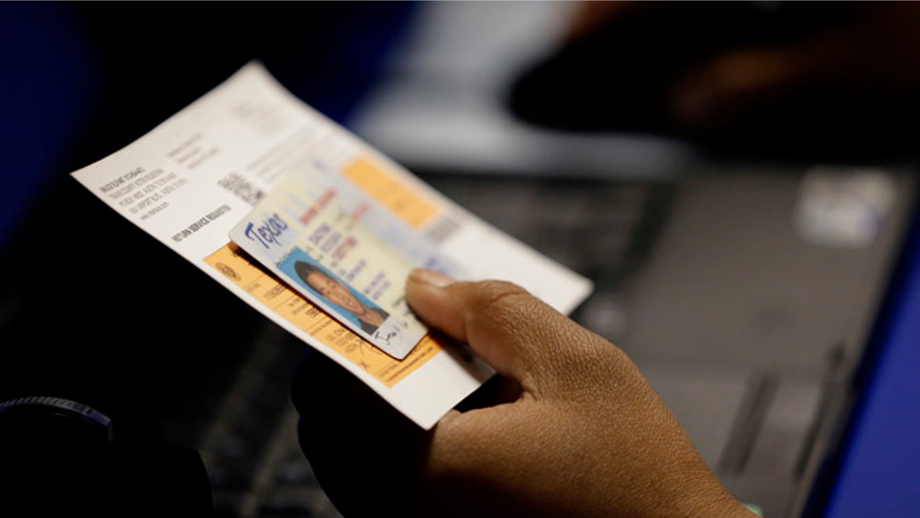FILE - In this Feb. 26, 2014, file photo, an election official checks a voter's photo identification at an early voting polling site in Austin, Texas. A federal appeals court ruled Wednesday, July 20, 2016, that Texas' strict voter ID law discriminates against minorities and the poor and must quickly be scrubbed of those effects before the November 2016 election. Voters will still need to show identification at the polls under the decision by the New Orleans-based 5th U.S. Circuit Court of Appeals, according to attorneys who challenged the law, but a lower court will now also have to devise a way for Texas to accommodate those who cannot. (AP Photo/Eric Gay, File)