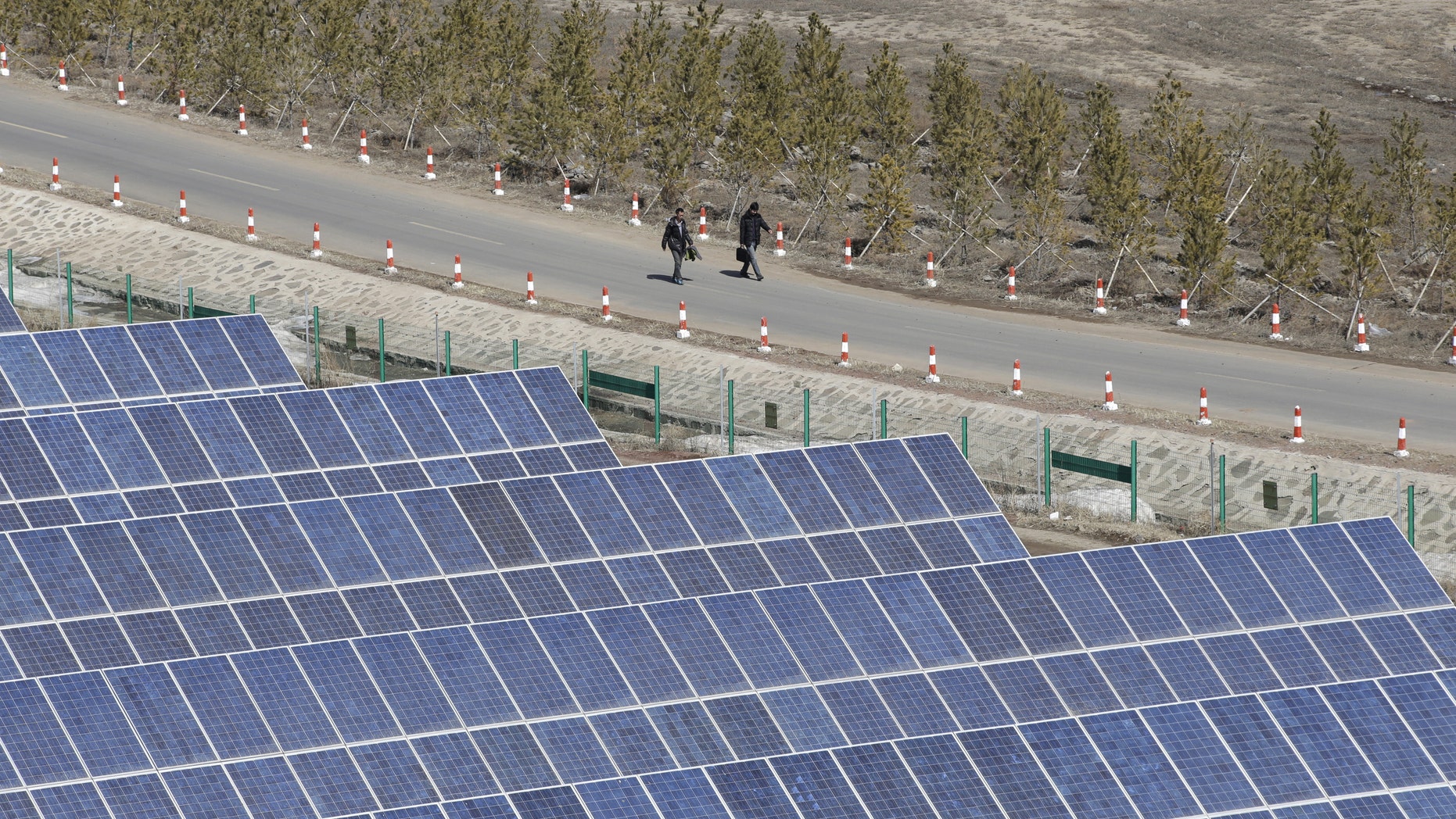 File photo - People walk past the solar panels at a wind and solar energy storage and transmission power station of State Grid Corporation of China, in Zhangjiakou of Hebei province, China, March 18, 2016. (REUTERS/Jason Lee)
