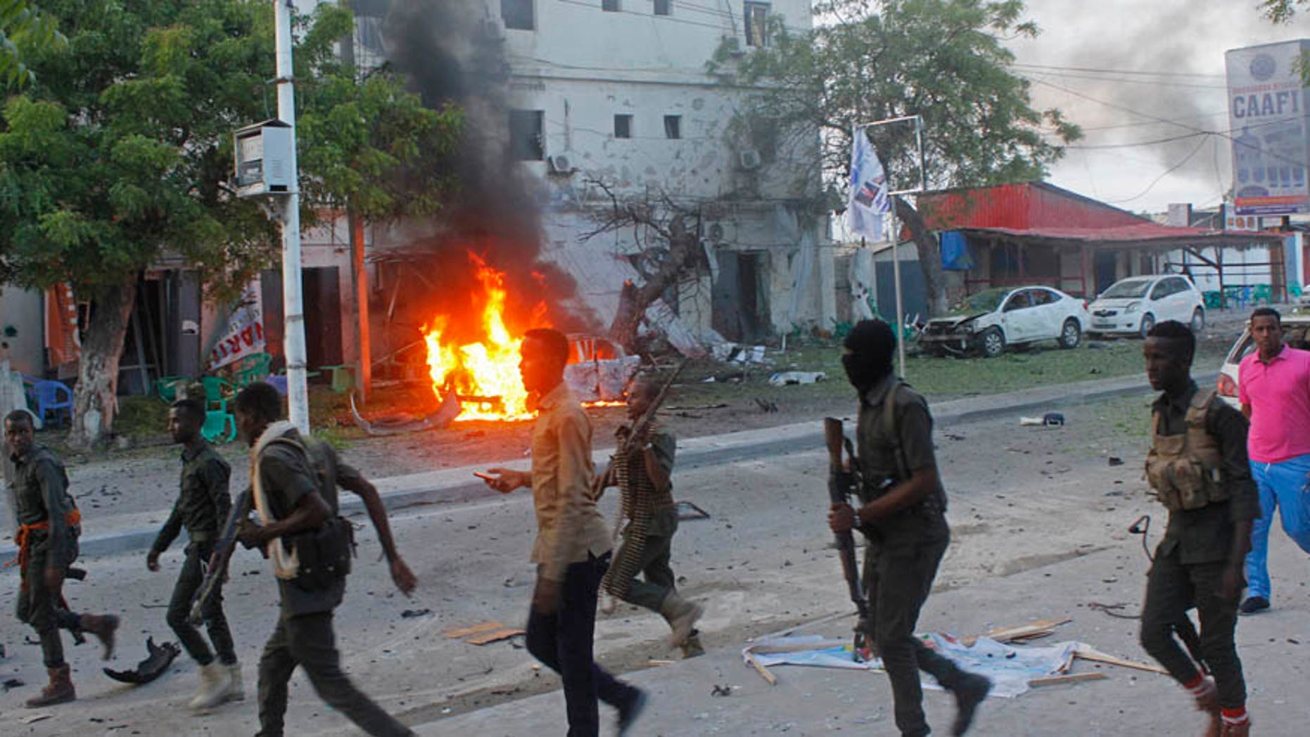 May 8, 2017: Somali security walk near a burning car after a car bomb attack on a restaurant in Mogadishu, Somalia.