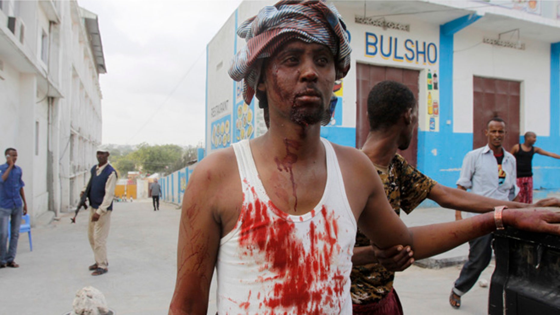 Mar. 27, 2015: A Somali man helps a wounded civilian who was injured by a car bomb that detonated at the gate of one of Mogadishu's most popular hotel. (AP)