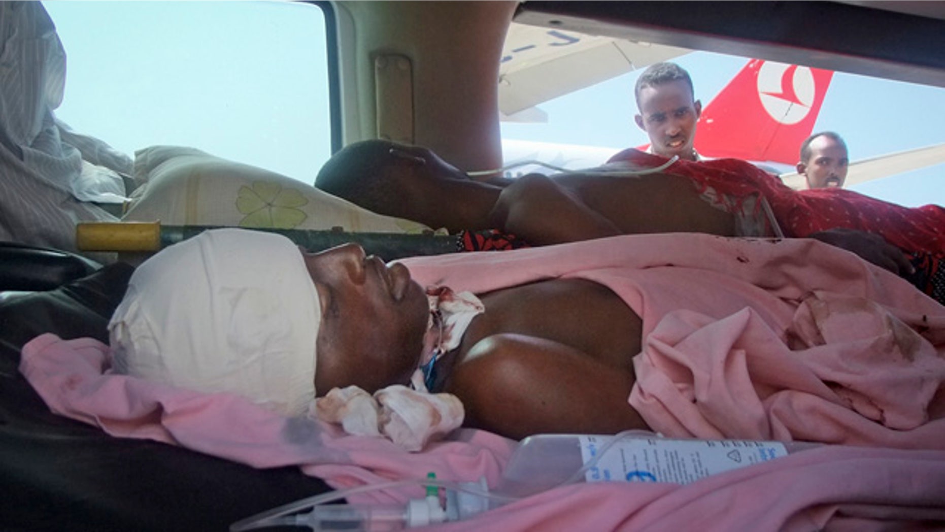 Oct. 6: Two patients, one still alive, top, and one who died en route to the airport, bottom, arrive in an ambulance at an aircraft flying wounded patients from Tuesday's suicide bombing to Turkey for treatment, at the airport in Mogadishu, Somalia.