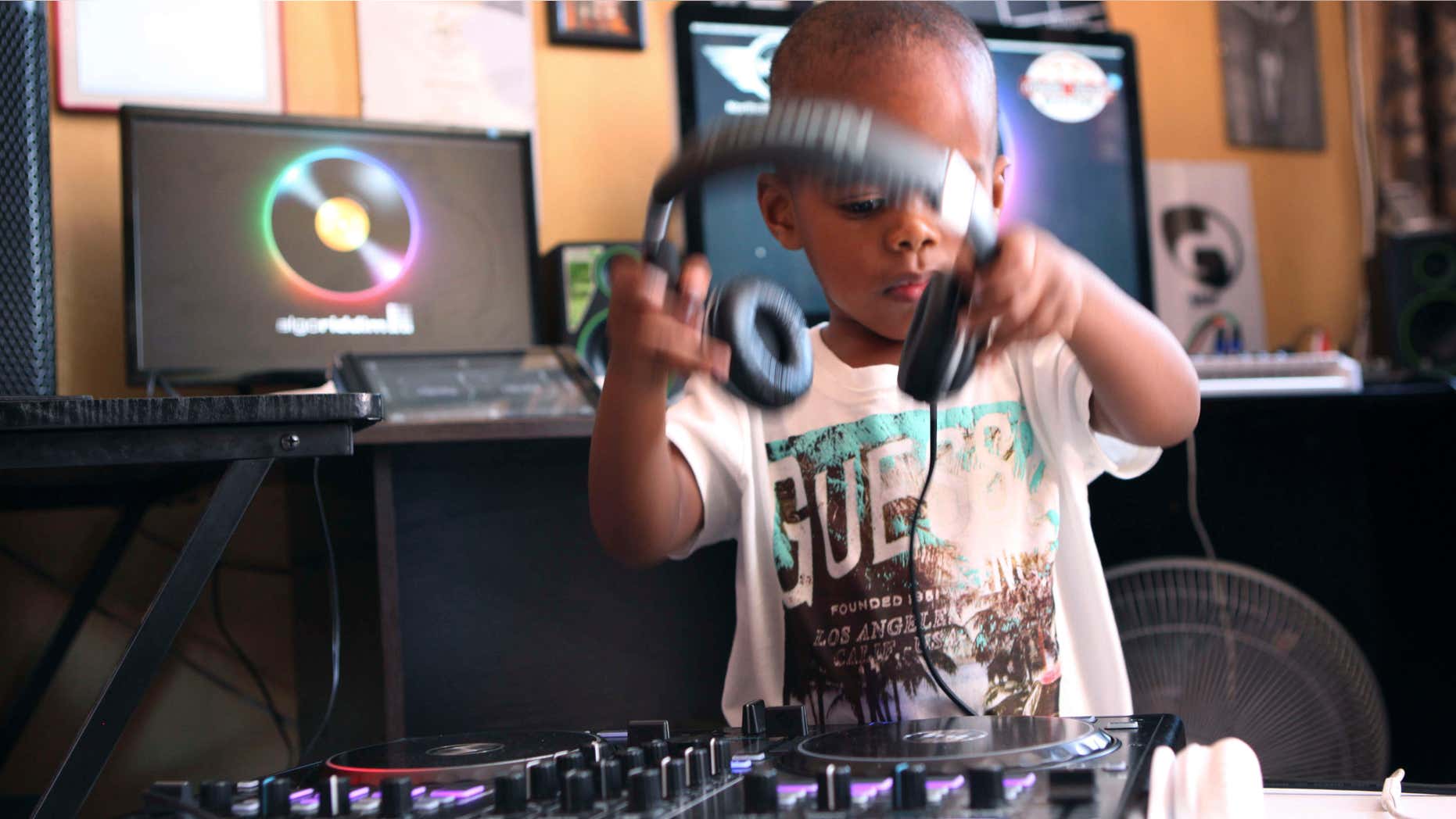 April 6, 2015: Two-year-old Oratilwe Hlongwane, also known as DJ AJ to his fans, removes his headphones after playing with the buttons and knobs of a sophisticated music system in control of the beat of the bass-heavy house music at his Alexandra home in Johannesburg.