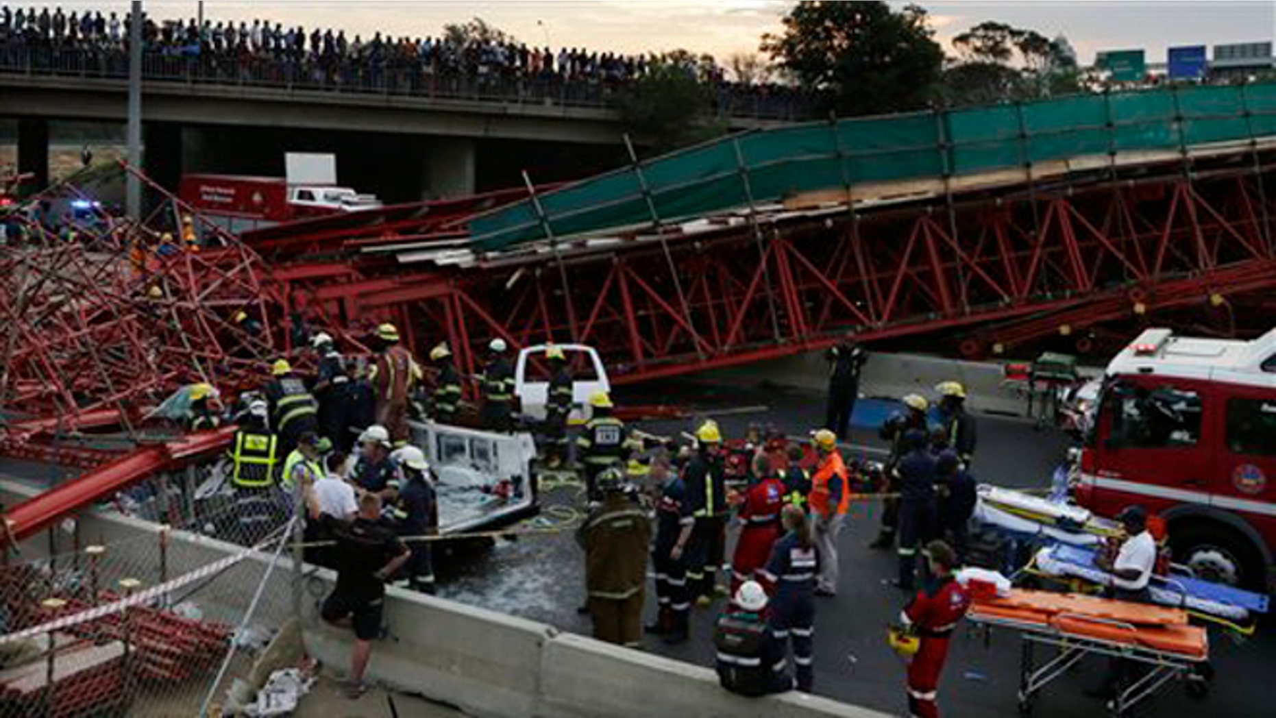 Oct. 14, 2015: Emergency service workers and paramedics help an injured man from a vehicle, which was partly crushed beneath scaffolding after a temporary bridge collapse in Johannesburg, South Africa.