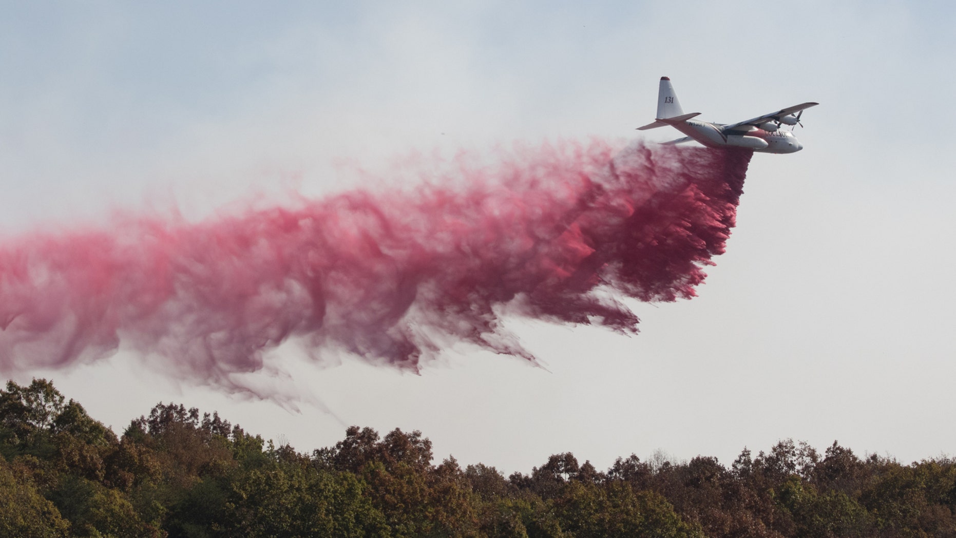 An aircraft from the US Forestry Service drops fire retardant on a wildfire burning along the Flipper Bend area of Signal Mountain in Hamilton County, Tenn., on Wednesday.