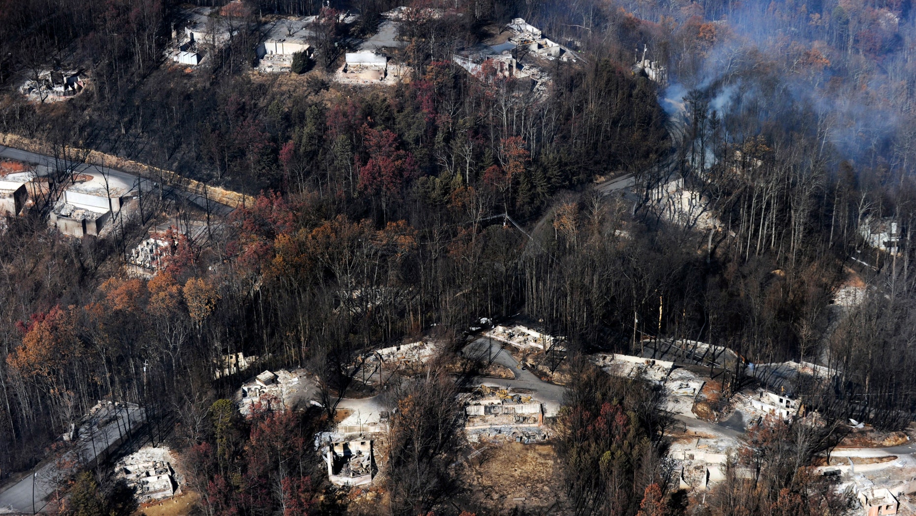 FILE - In this Tuesday, Nov. 29, 2016, file photo, smoke rises from destroyed homes, many burned down to the foundation, the day after a wildfire that hit Gatlinburg, Tenn. Experts said that escaping a fire-filled forest, as thousands did Nov. 28 in the Great Smoky Mountains, can be more traumatic than disasters such as hurricanes, floods or earthquakes. One reason: Flames that scorched neighborhoods in the Gatlinburg, Tenn., area spread so rapidly that people had no time to brace for it. (Paul Efird/Knoxville News Sentinel via AP, File)