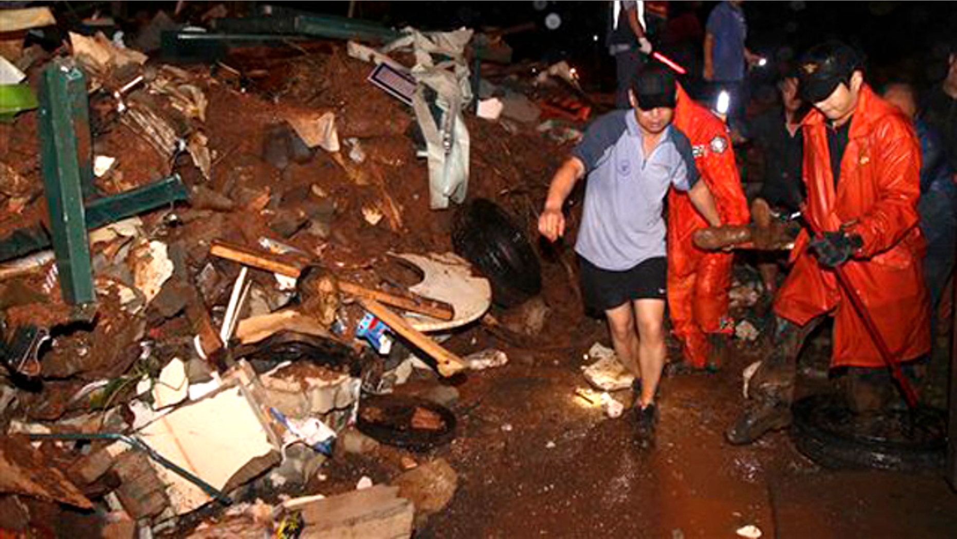 South Korean rescue workers carry a survivor who was rescued from a collapsed house as a midnight landslide caused by torrential rains swept away several houses in Chuncheon, South Korea, Wednesday, July 27, 2011.
