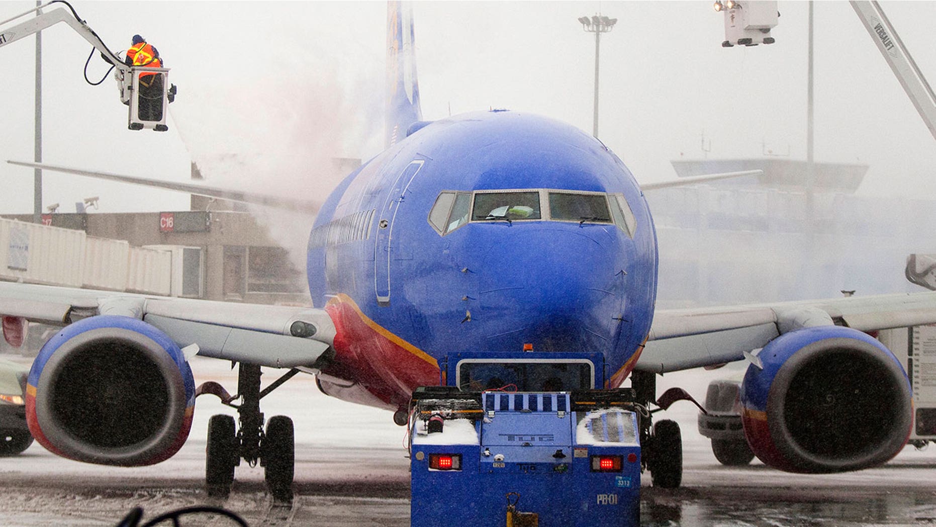 Southwest Airlines crew members are seen de-icing an aircraft at Boston's Logan International Airport in 2014. The airline recently confirmed that a lack of de-icing fluid was responsible for flight cancellations in Chicago on Sunday.