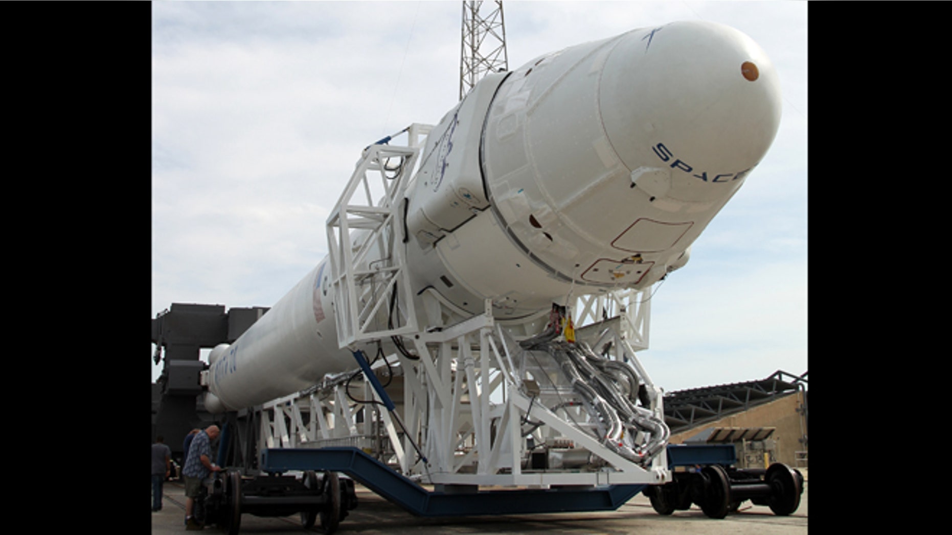 The Dragon spacecraft and its Falcon 9 rocket, both made by SpaceX, are rolled to the launch pad ahead of the static firing test for the rocket.