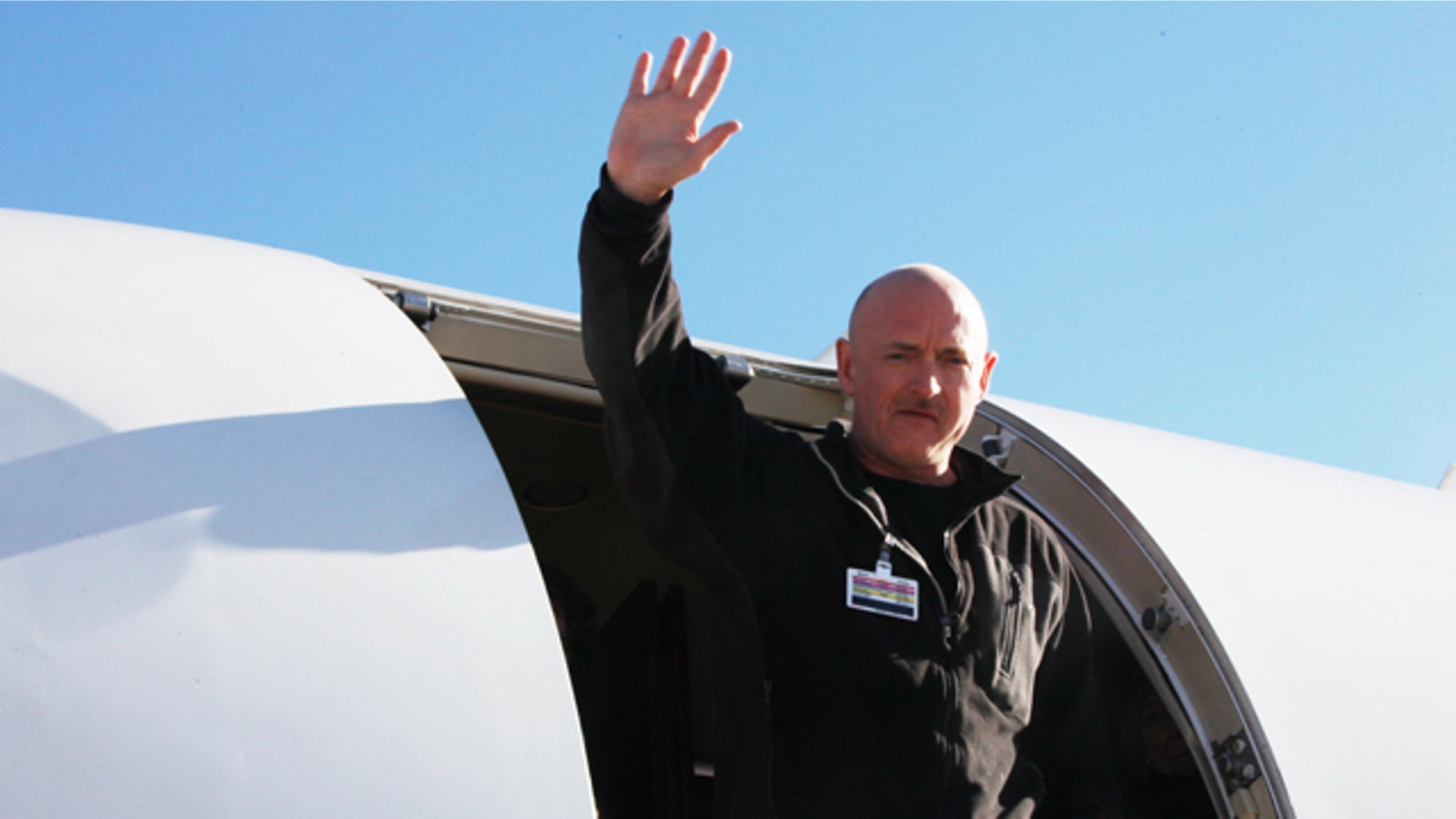 Astronaut Mark Kelly waves after his Rep. Giffords was loaded onto an airplane in Tucson, Ariz., as she is transferred to a rehabilitation center in Houston, Friday, Jan. 21, 2011.