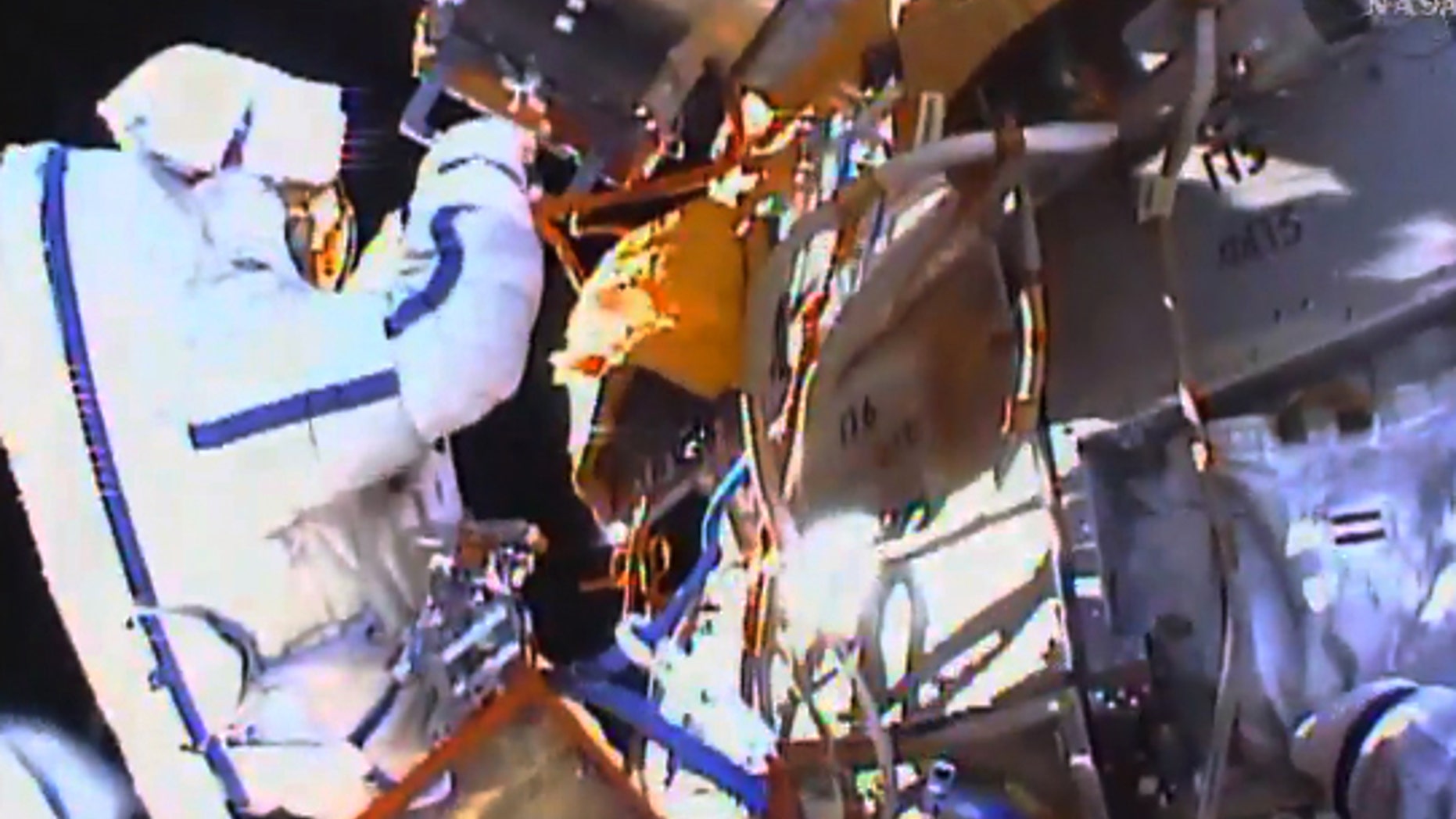 This photo taken from video provided by NASA shows Russian cosmonauts Yuri Malenchenko and Sergey Volkov install fresh experiments outside the International Space Station on Wednesday, Feb. 3, 2016. The spacewalkers set off to retrieve biological samples that have been outdoors seven years, and put out some new science trays. They also planned to test a new glue that might prove useful in years to come on the station's exterior. (NASA via AP)