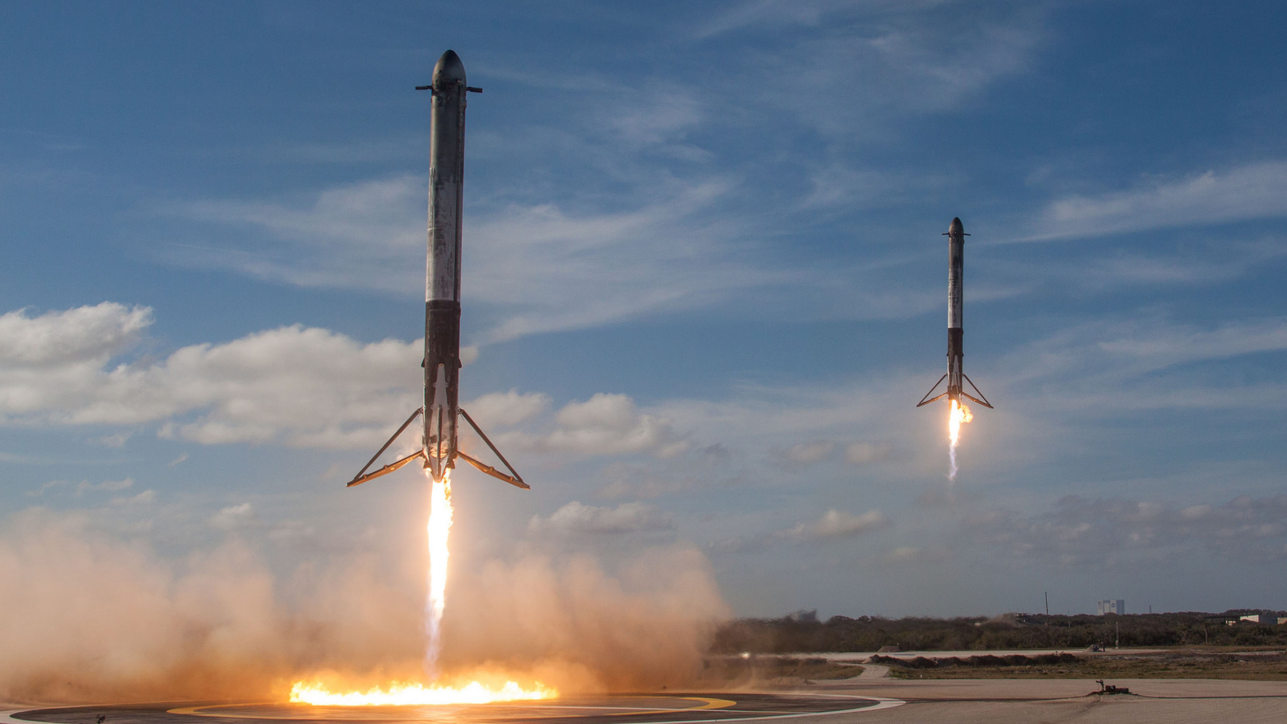 Two SpaceX Falcon Heavy boosters make a simultaneous landing after launching the first Falcon Heavy rocket into orbit on Feb. 6, 2018. Elon Musk says SpaceX will soon try to land the upper stage of its workhorse Falcon 9 rocket using a "giant party balloon."
